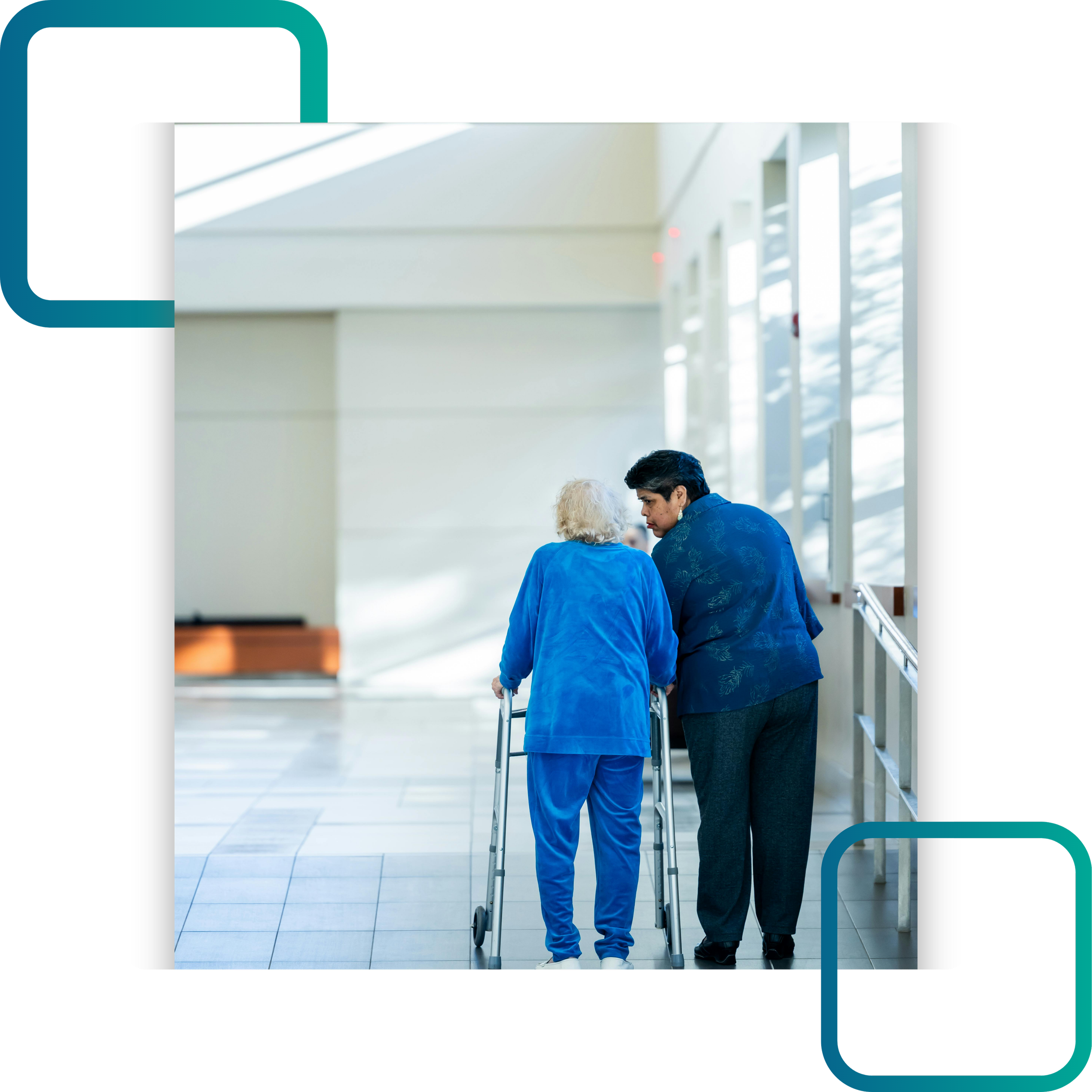 An elderly person with white hair is using a walker and is being assisted by a middle-aged woman in a blue patterned shirt, inside a modern building with large windows and natural lighting.