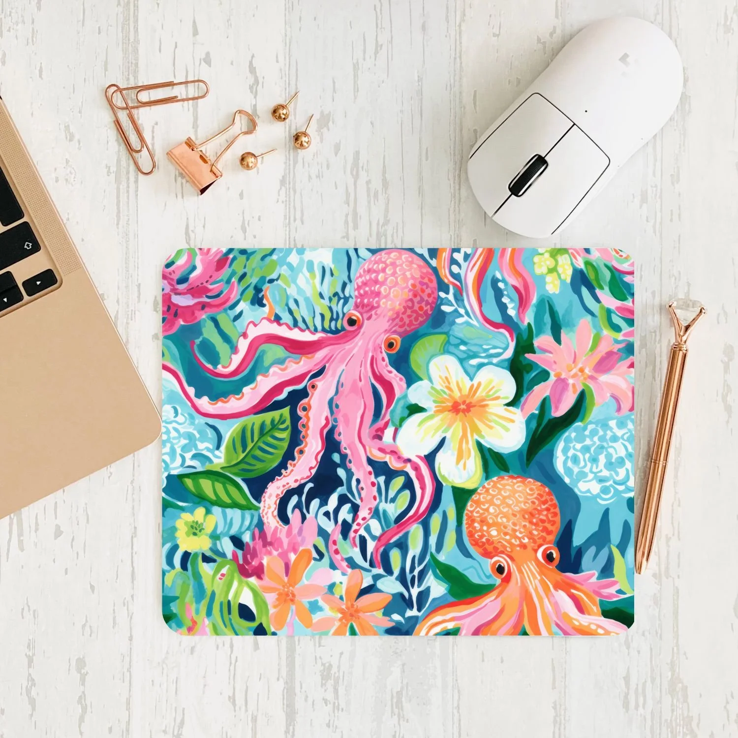 Colorful mouse pad with an ocean theme featuring pink octopuses and tropical flowers on a white desk.