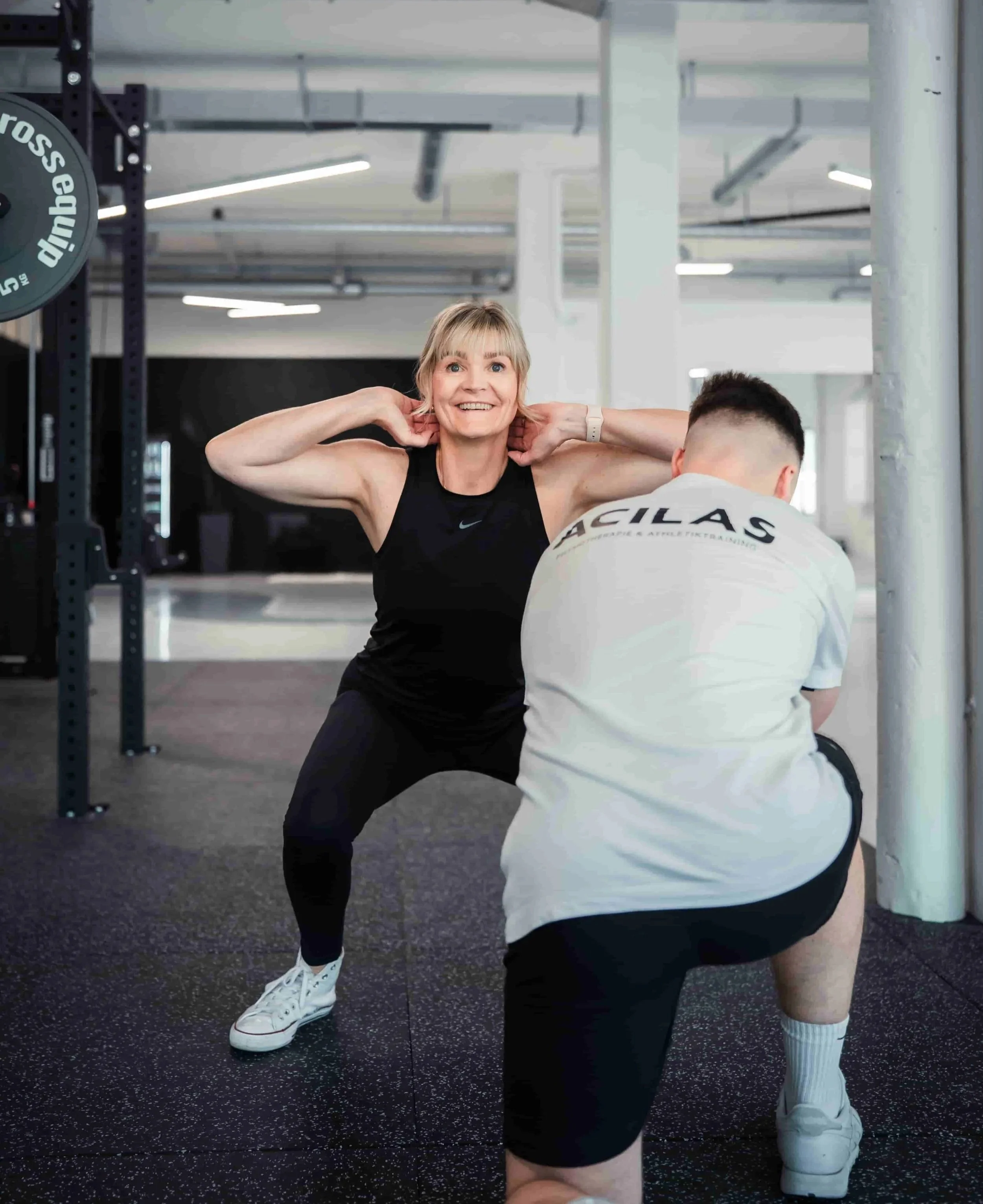 Eine Frau trainiert mit einem Personal Trainer im Fitnessstudio.