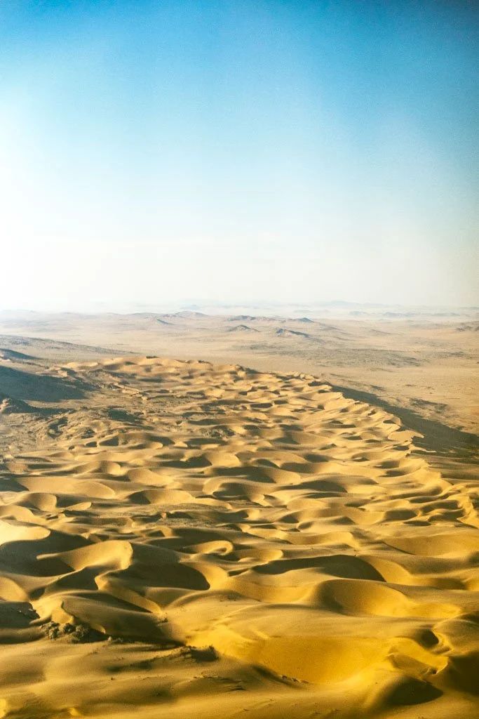A desert scene with sand dunes and a clear blue sky.
