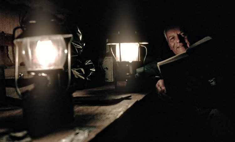 Dr. Maynard Miller reads by lantern light.  Photo:  S. McGee