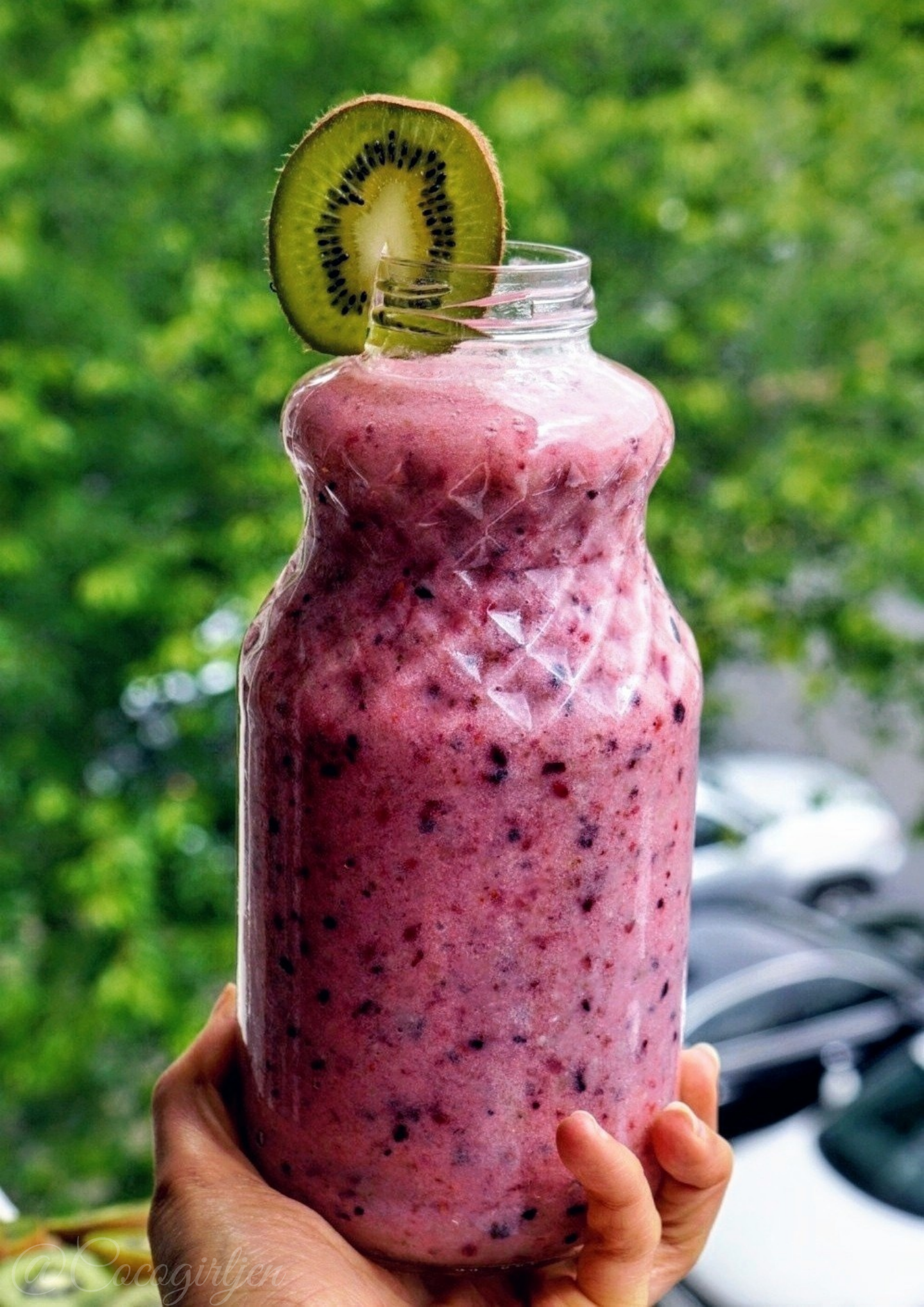 Raw vegan breakfast smoothie in a pretty glass bottle with a kiwi slice garnish.