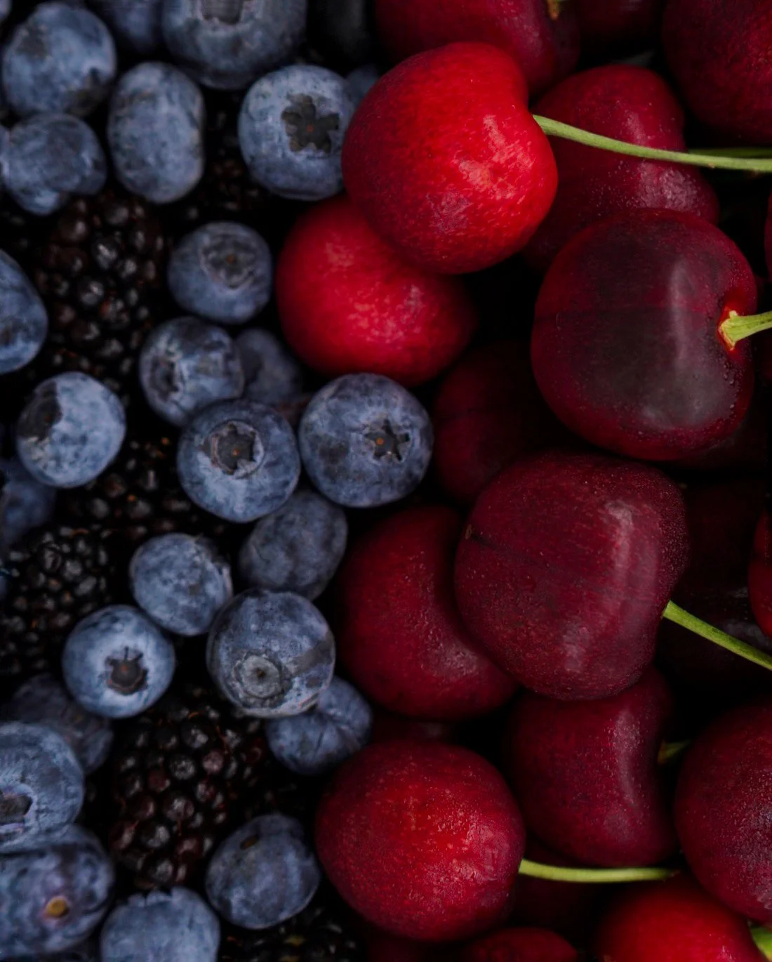 An assortment of blueberries and cherries closely arranged.