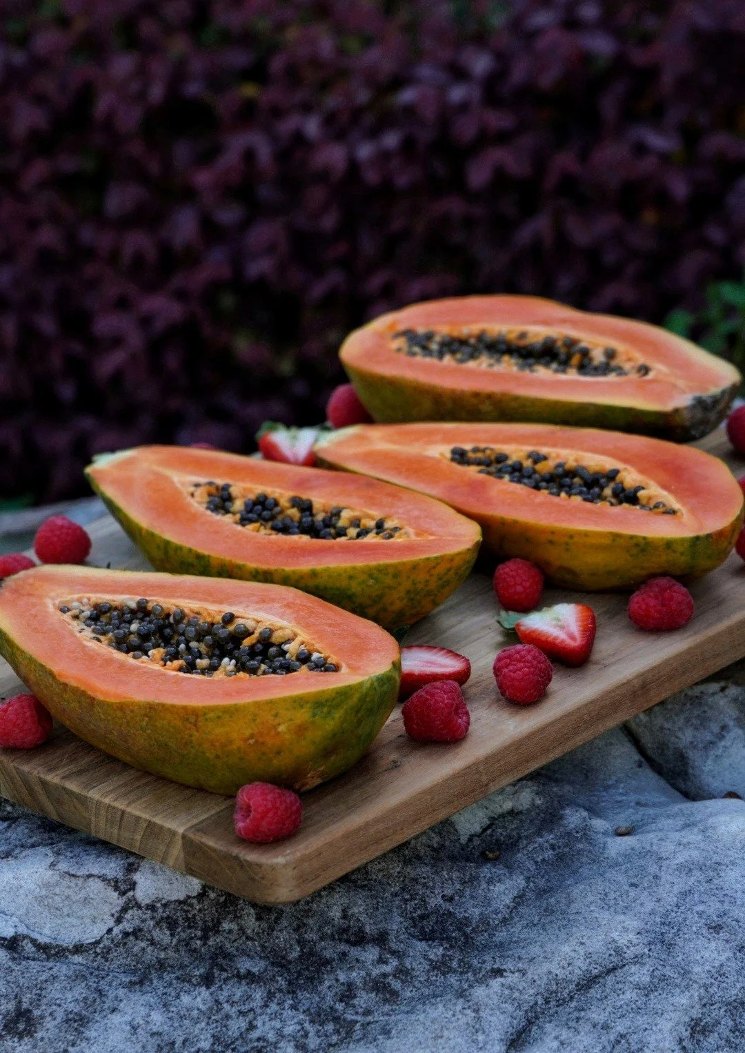 Papaya fruit platter with strawberries and two vibrant papayas cut in half.