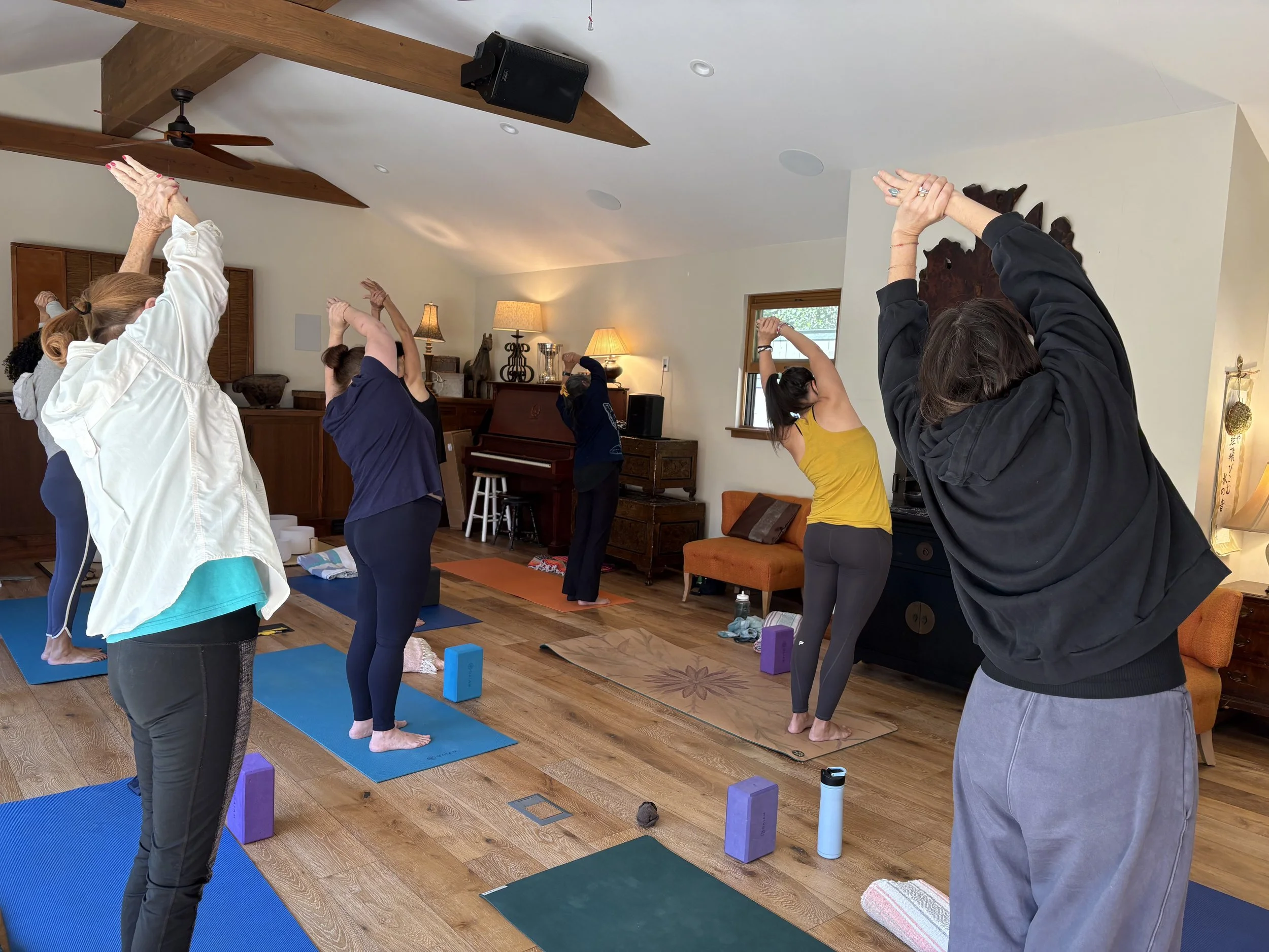 A group of people standing on yoga mats standing and leaning to the side.