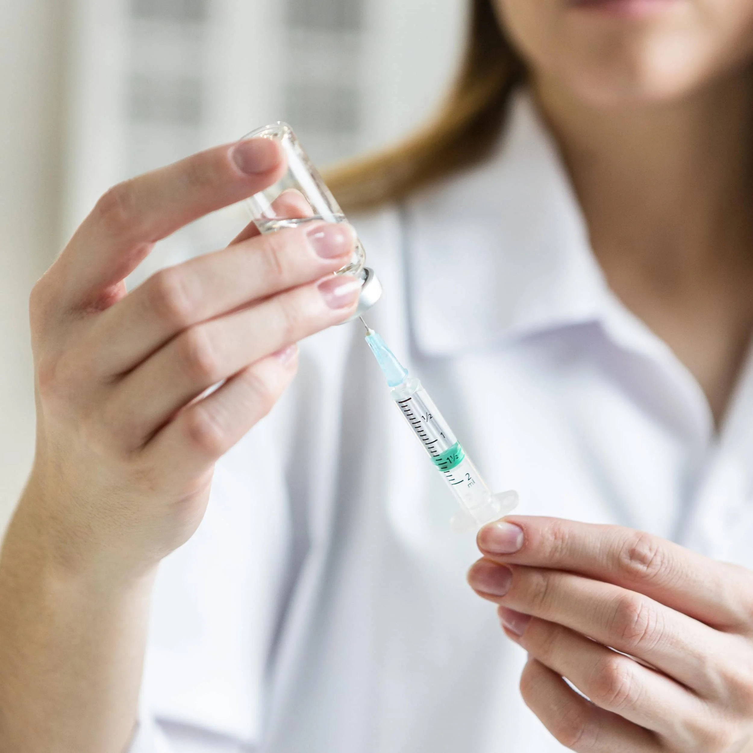 defocused-female-scientist-with-safety-glasses-holding-syringe-with-vaccine (1)-min.jpg