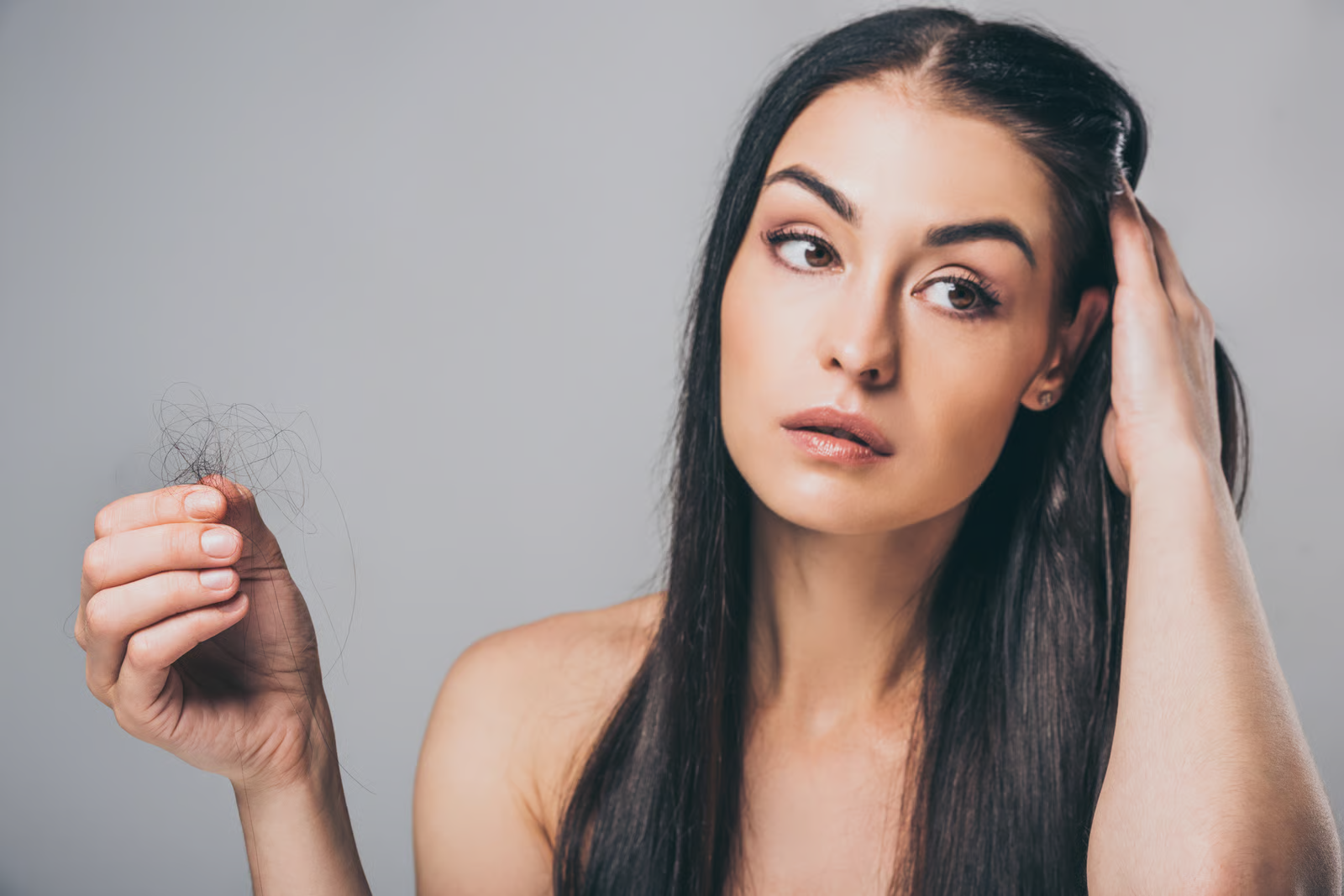 Woman noticing early signs of hair loss and hair thinning due to stress.