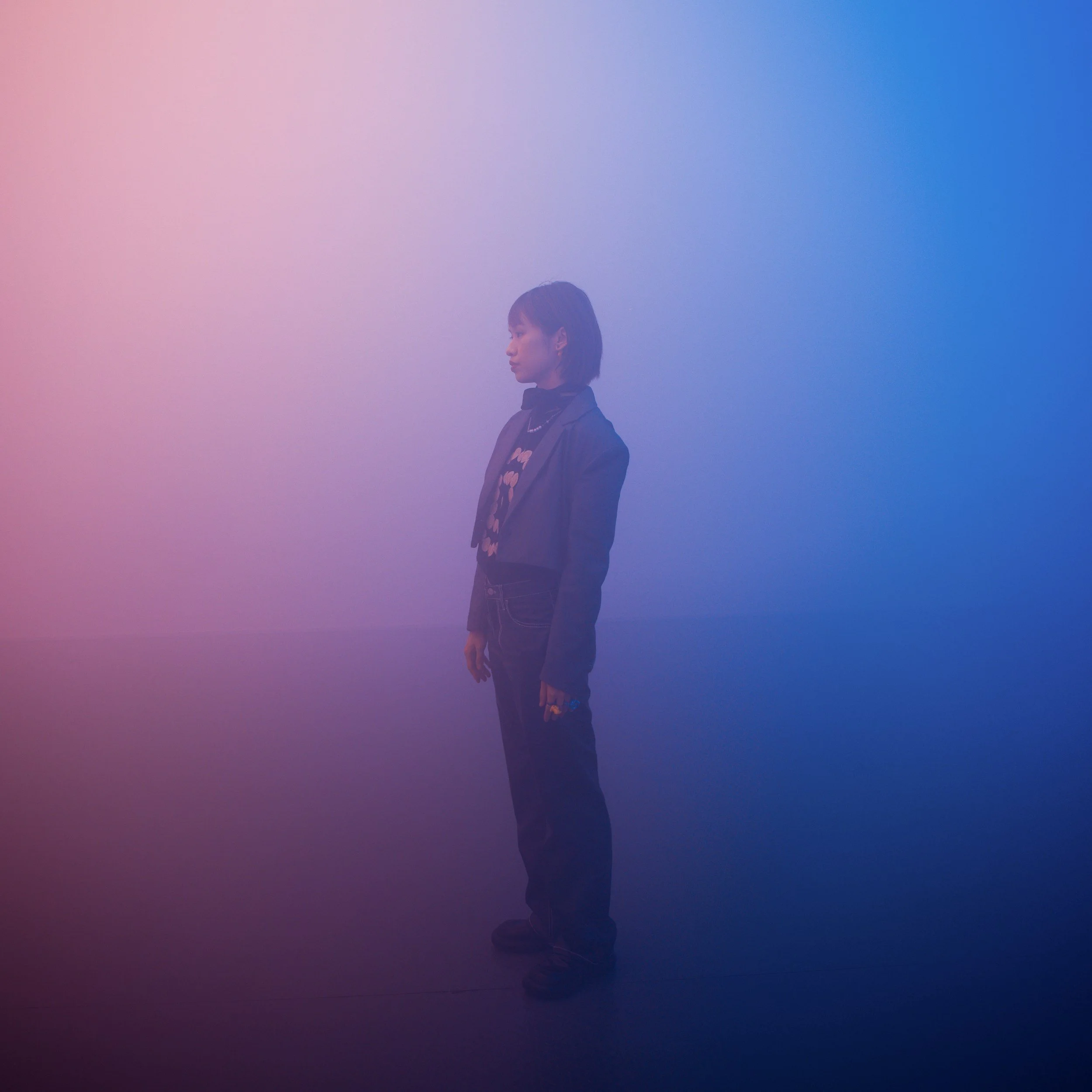 A child standing inert faded into the background with pink and blue mist