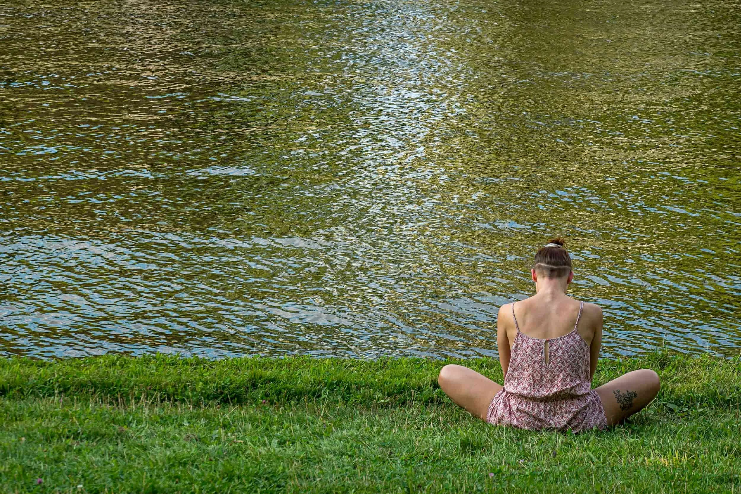 Woman sat by a lake doing breathwork
