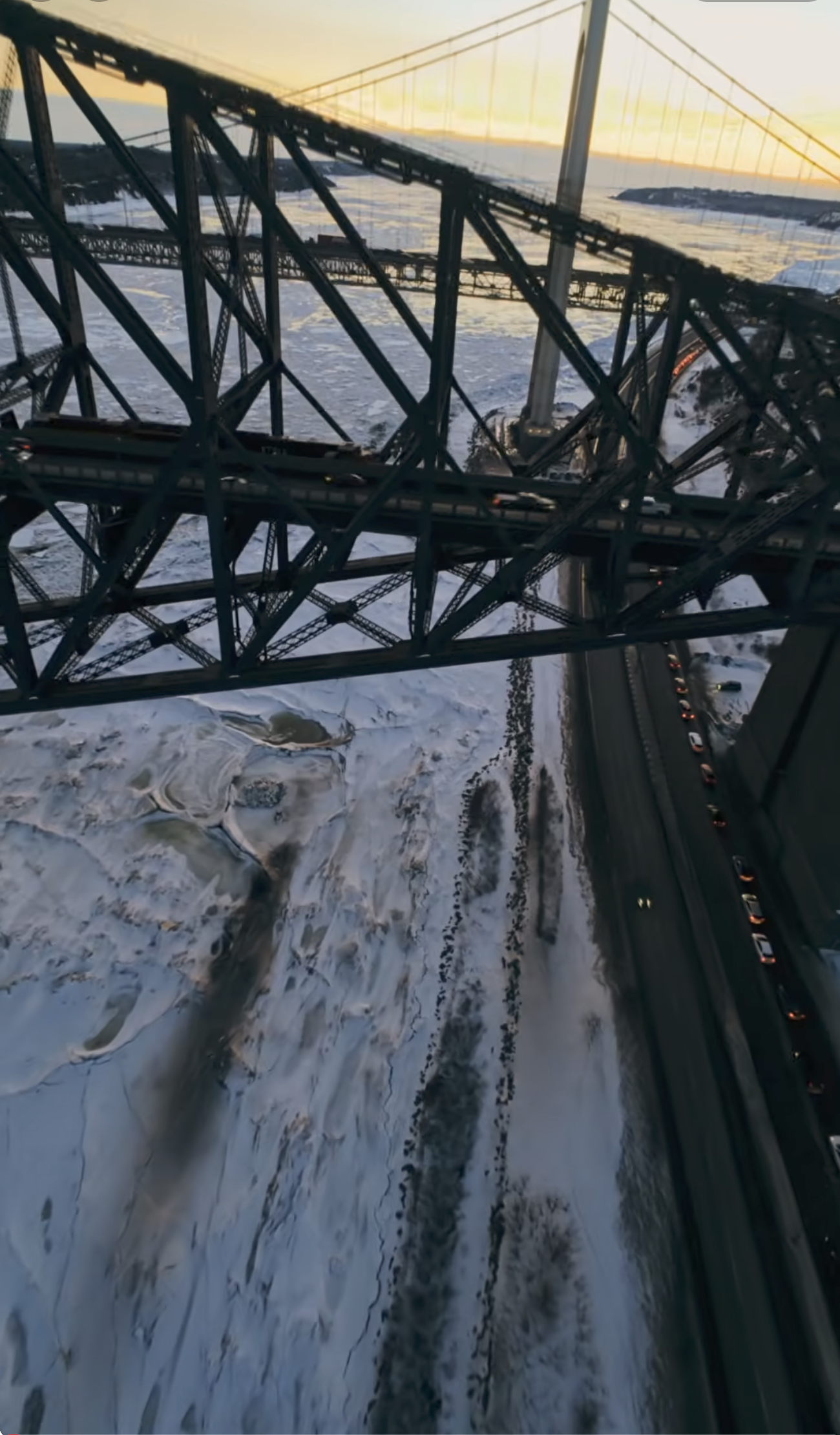 Plan aérien par drone FPV sous la structure d'acier du pont de Québec au-dessus des glaces du fleuve, LensBrothers