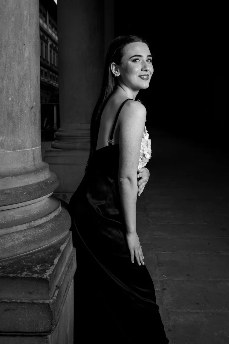 Diciottesimo in bianco e nero: ragazza in abito nero tra le colonne, foto di Matilde Rindi, fotografa a Prato