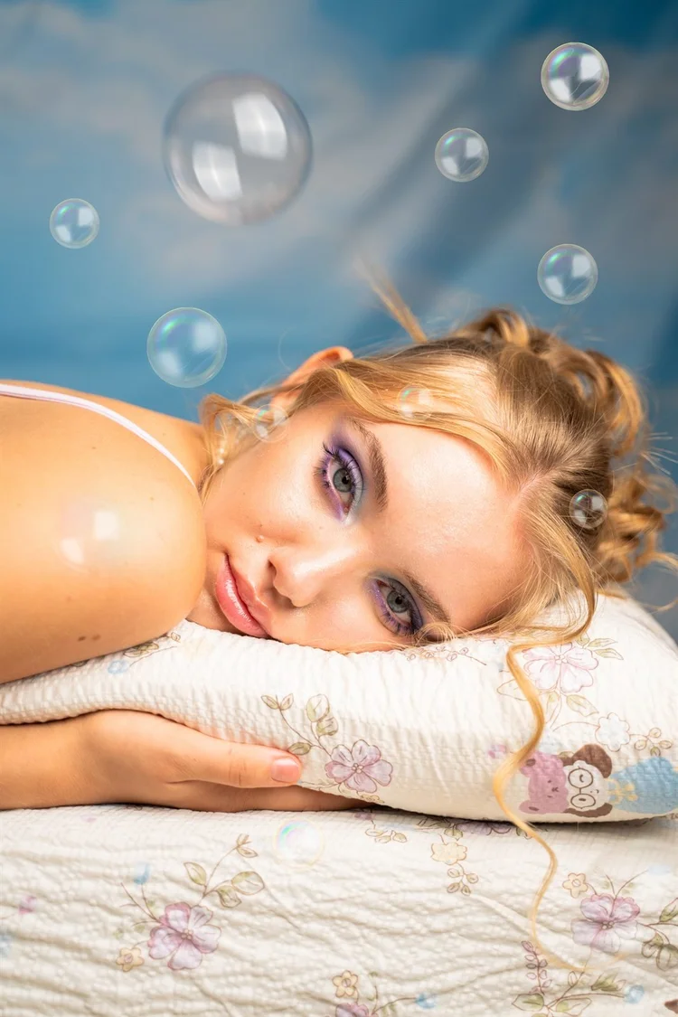 Servizio editoriale: ragazza bionda sdraiata su un cuscino tra bolle di sapone, foto di Matilde Rindi, fotografa a Prato