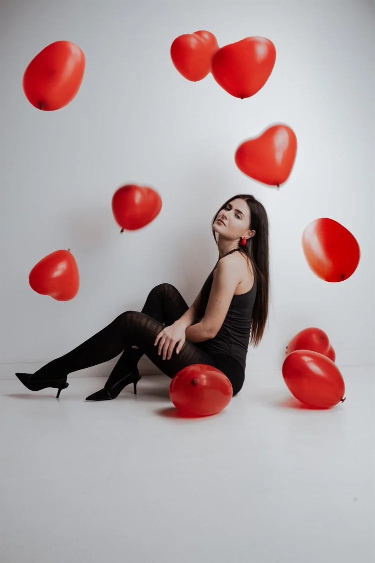 Ritratto creativo in studio con palloncini rossi a forma di cuore