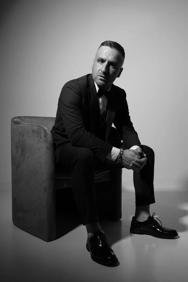 Book attore in bianco e nero, figura intera seduto su un cubo in studio, foto di Matilde Rindi, fotografa a Prato