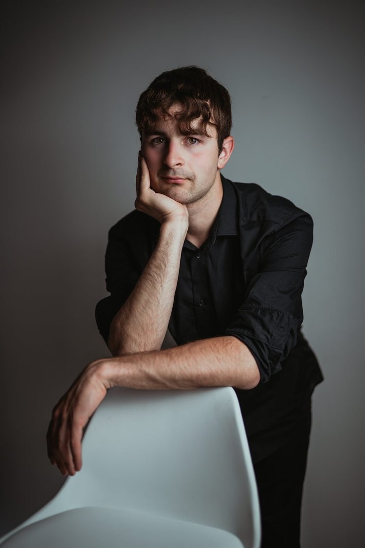 Book attore con camicia nera seduto su una sedia bianca, foto di Matilde Rindi, fotografa a Prato