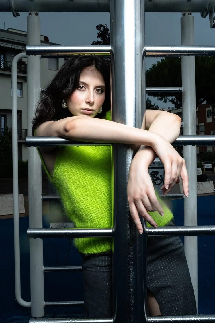 Book per modelli: ragazza con maglione verde appoggiata a un cancello, foto di Matilde Rindi, fotografa a Prato