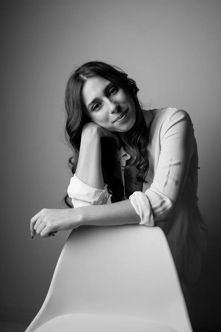 Book attrice in bianco e nero appoggiata a una sedia, sorridente, foto di Matilde Rindi, fotografa a Prato