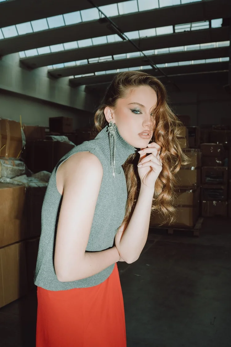 Book per modelli: ragazza con dolcevita verde e gonna rossa in un magazzino, foto di Matilde Rindi, fotografa a Prato