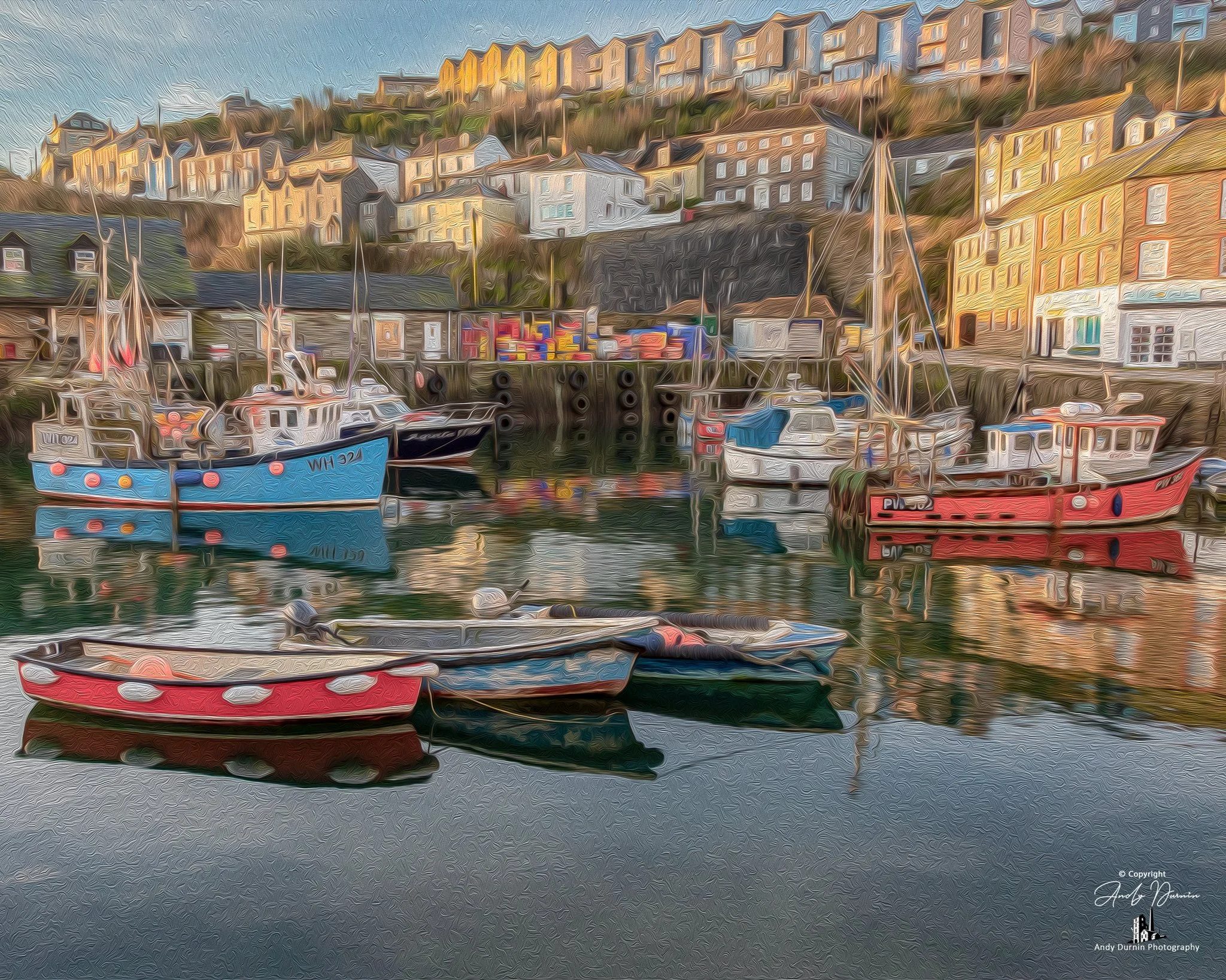 Mevagissey Harbour.  Boats moored in a harbour with colourful houses and buildings on a hillside in the background.