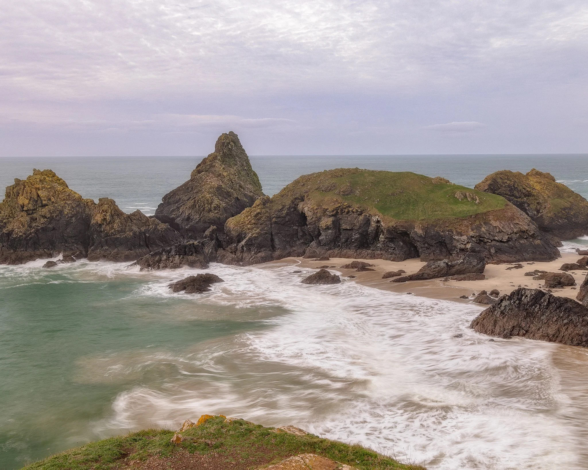 Asparagus Island at Kynance Cove on The Lizard Peninsula, surrounded by turquoise sea and rugged cliffs.