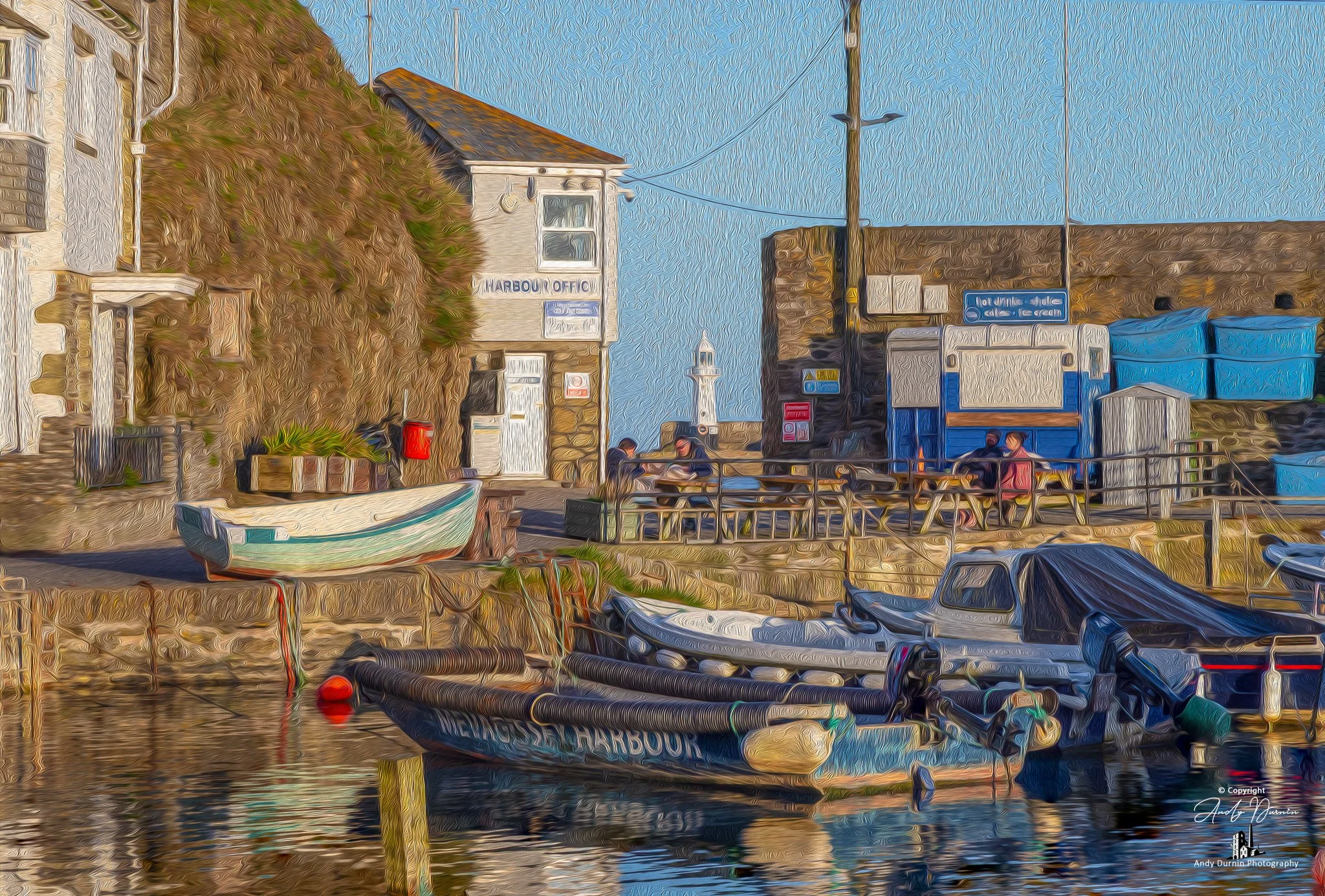 A painterly-style image of Mevagissey Harbour’s waterside buildings and boats, featuring the harbour office, small fishing craft, and warm late-afternoon light reflecting across the scene.