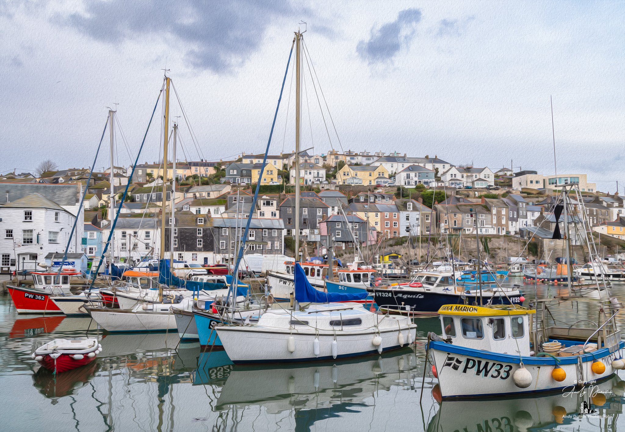 A peaceful harbour scene from Mevagissey Harbour in Cornwall, showing fishing boats and yachts moored in still water below the village houses on the hillside. This fine art coastal print captures the quiet charm of one of Cornwall’s best-known fishin