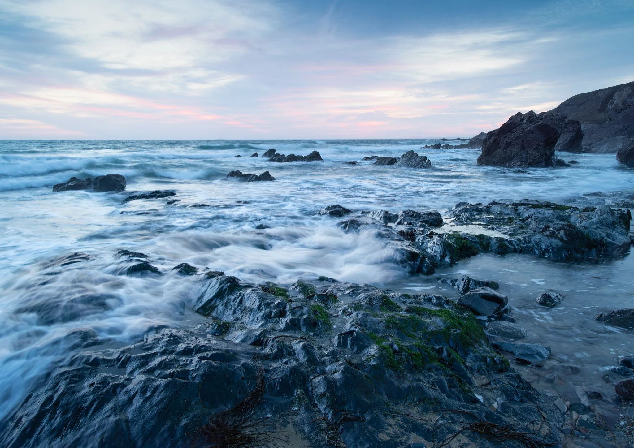 Dollar Cove Cornwall.  Ocean waves crashing on rocks at a rocky shoreline during sunset or sunrise