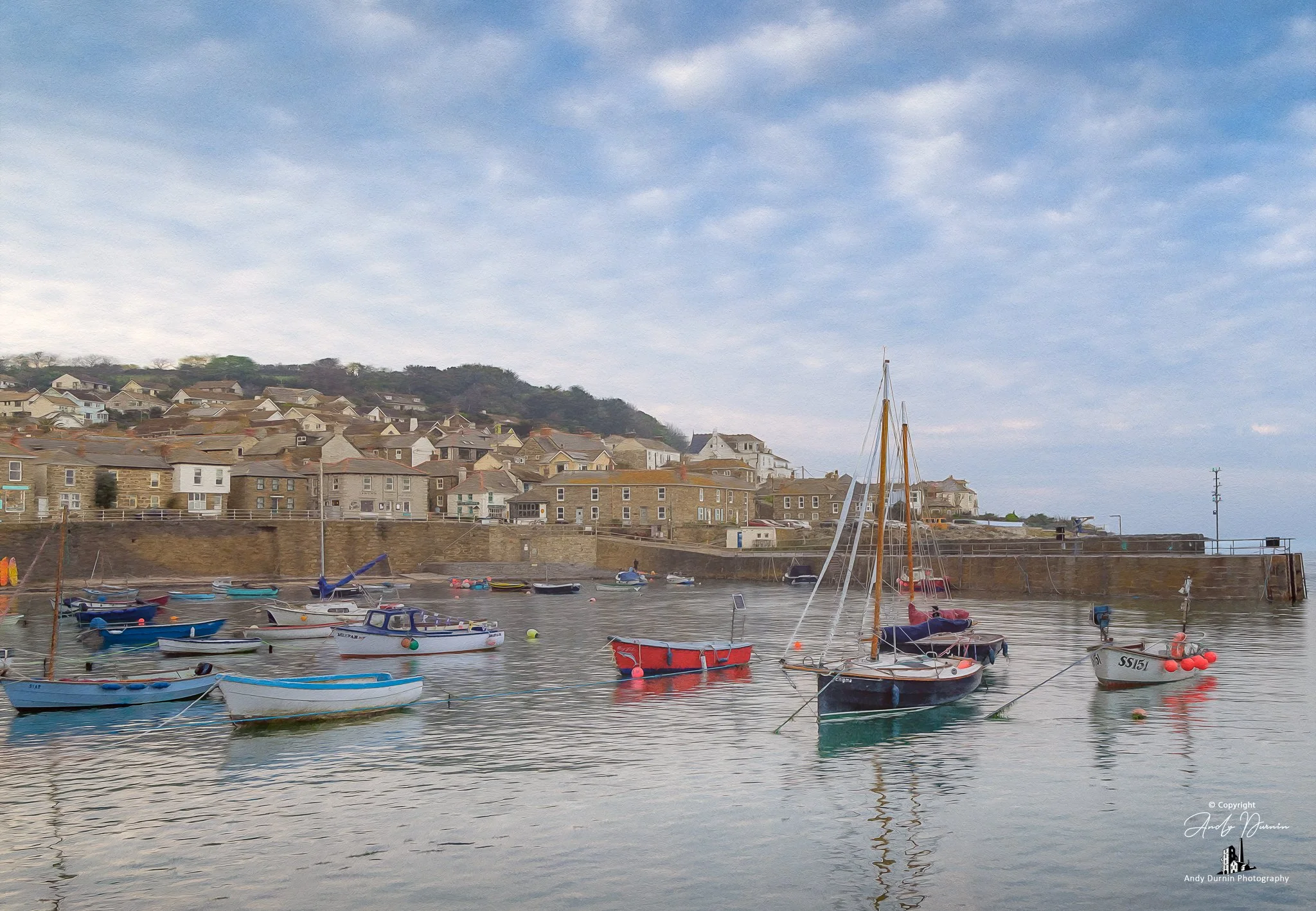This Mousehole Harbour print captures a broad and atmospheric view of the village, with fishing boats, calm water, old harbour walls and a softly textured sky. Presented in a painterly fine art style, this Cornwall coastal wall art print celebrates t