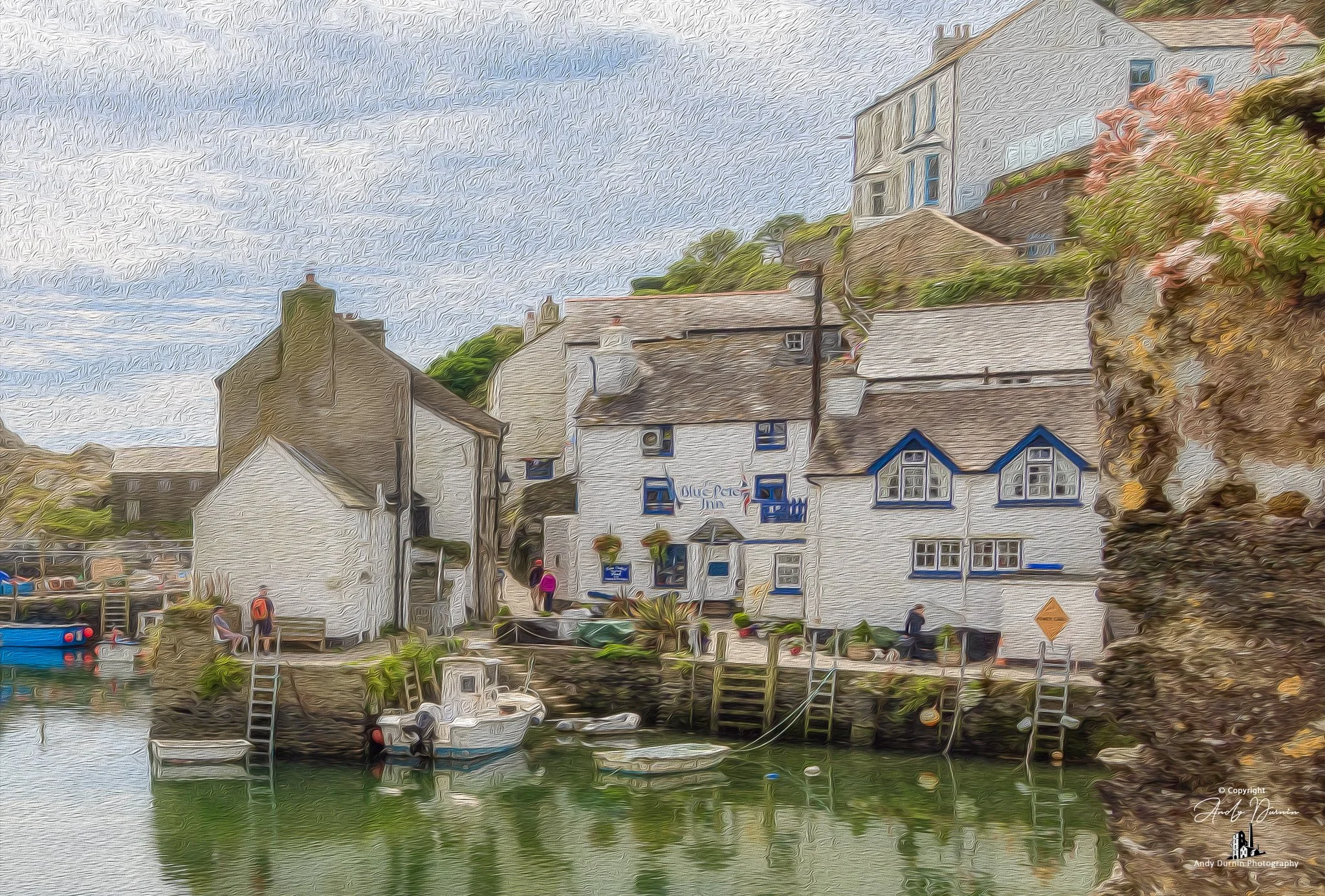 Polperro and the Blue Peter Inn along the water's edge, small boats docked, and people walking on the dock. The sky is cloudy.