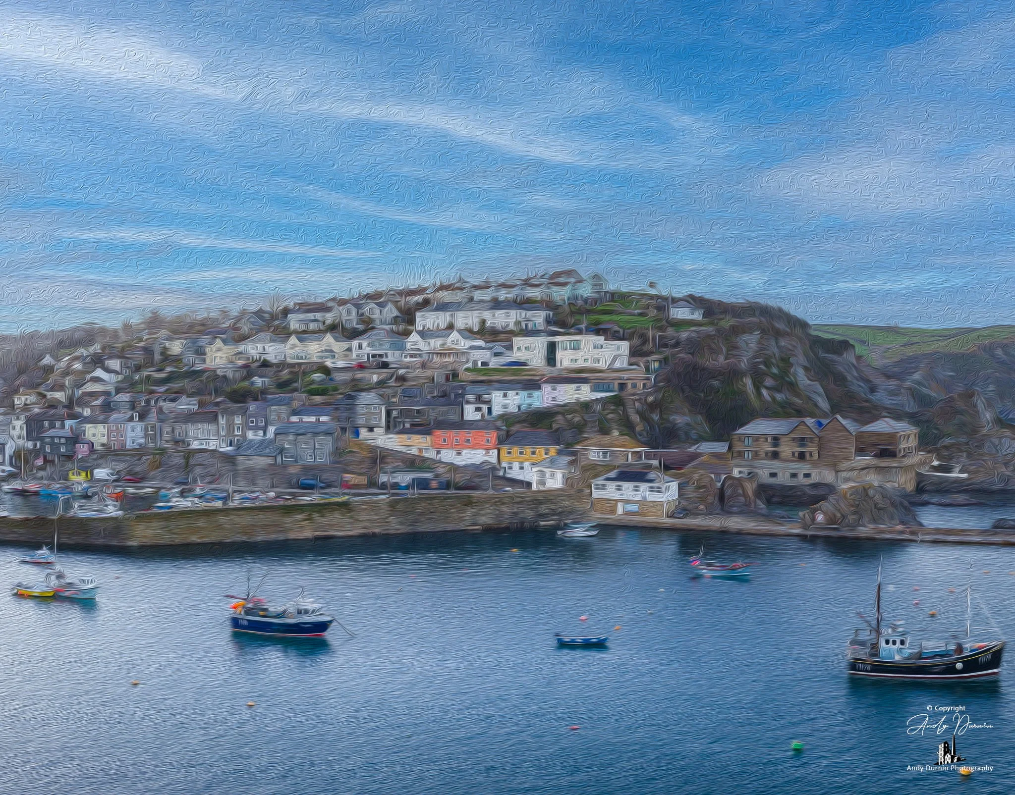 River Fowey Colorful boats floating in a harbor with a hillside town of houses and buildings in the background under a blue sky.