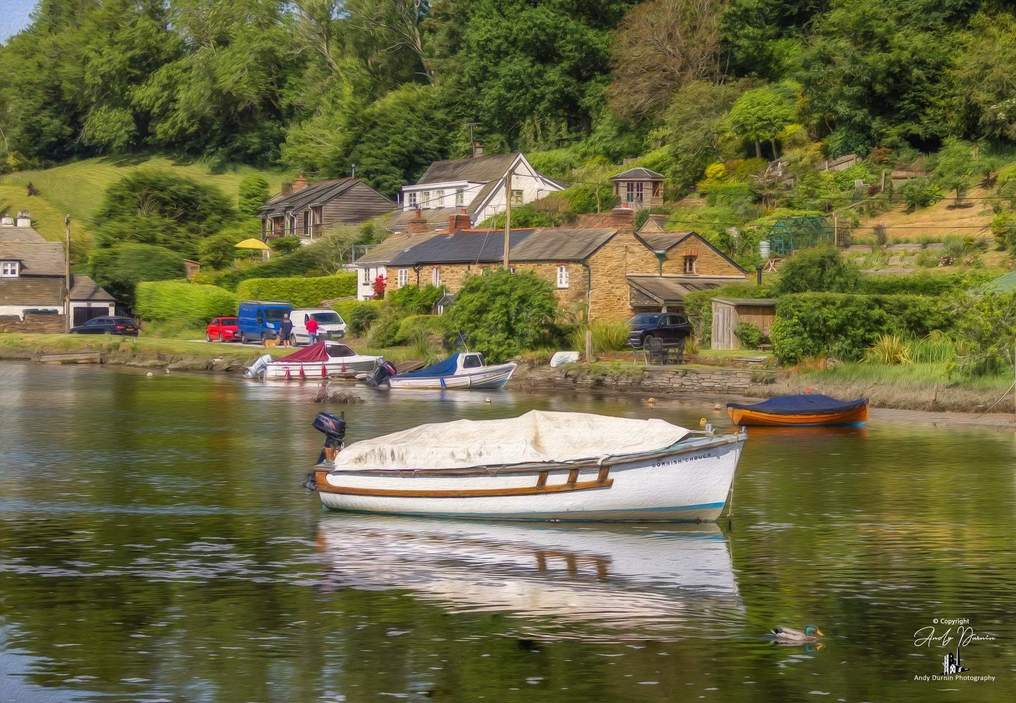 This fine art print of the River Lerryn at Lerryn in Cornwall captures a tranquil riverside scene with a traditional boat, calm reflections and charming village cottages nestled among lush green surroundings. A peaceful Cornwall landscape photograph 