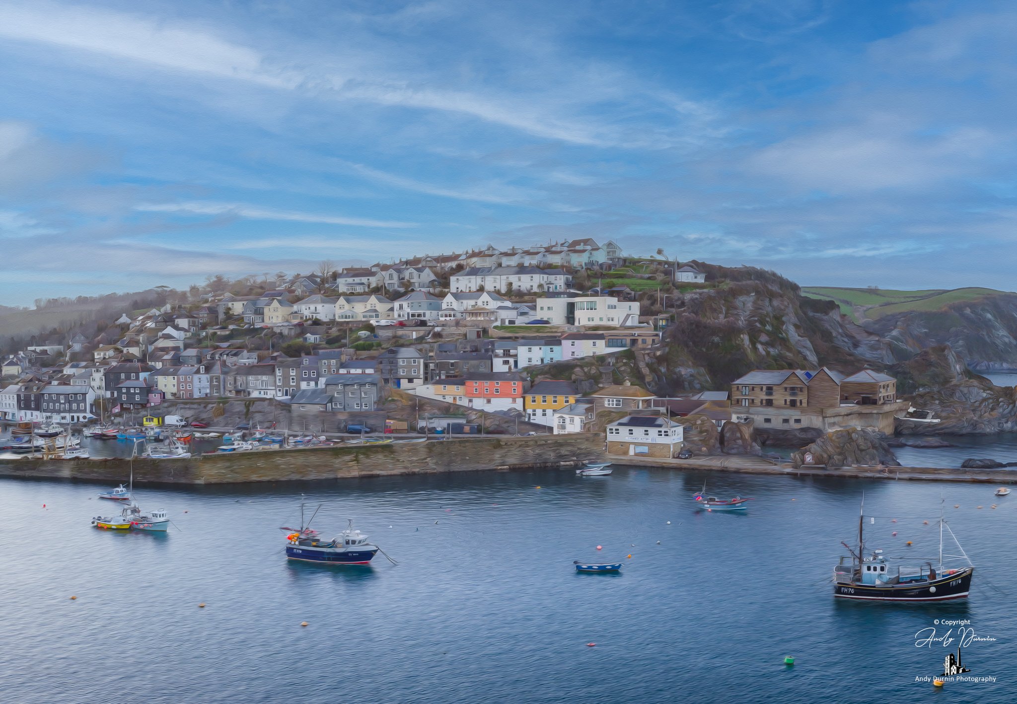This Mevagissey outer harbour print captures a peaceful view of one of Cornwall’s most iconic fishing villages, with boats on calm water, the harbour wall, traditional buildings and the coastline beyond. Finished in a painterly fine art style, this C