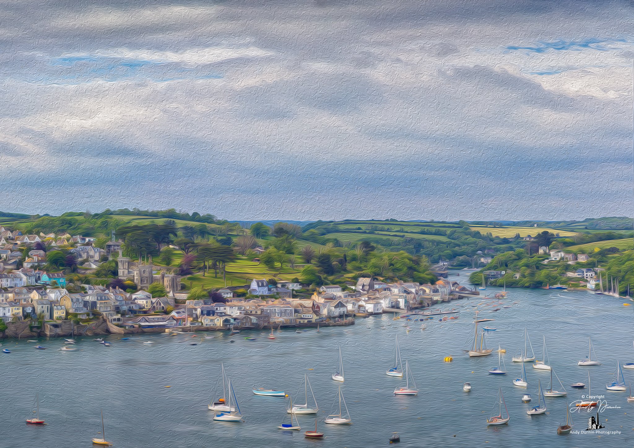Fowey and the River Fowey A riverside town with colourful houses and boats floating on the water, surrounded by green hills and a cloudy sky.
