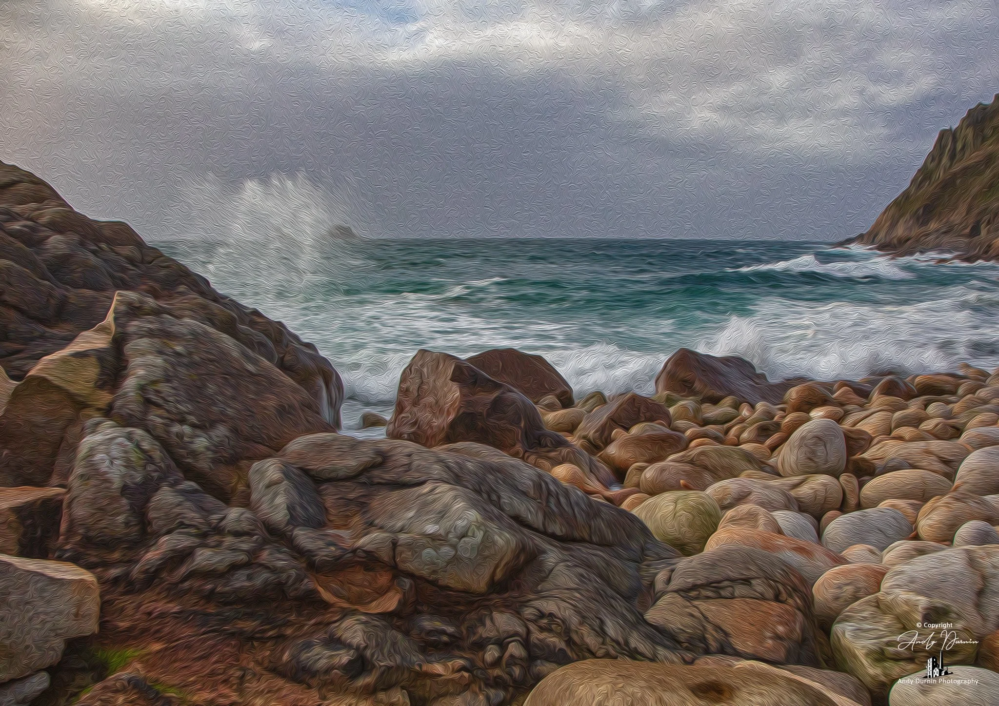 Porth Nanven (The Cot Valley).  A rocky shoreline with large boulders and pebbles, crashing waves, and a cloudy sky over the ocean, with cliffs on the right side.