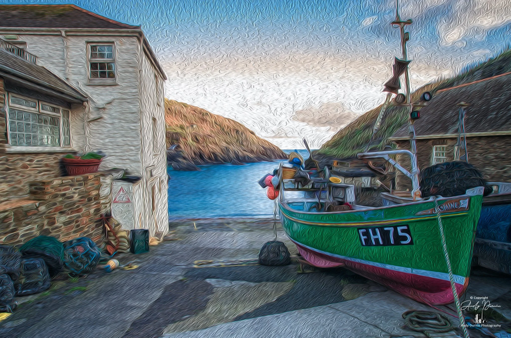Portloe, Cornwall.  A colourful boat with the registration FH75 on the slipway, with a narrow waterway and hills in the background, next to two rustic buildings, one with a white facade and the other with weathered wood.