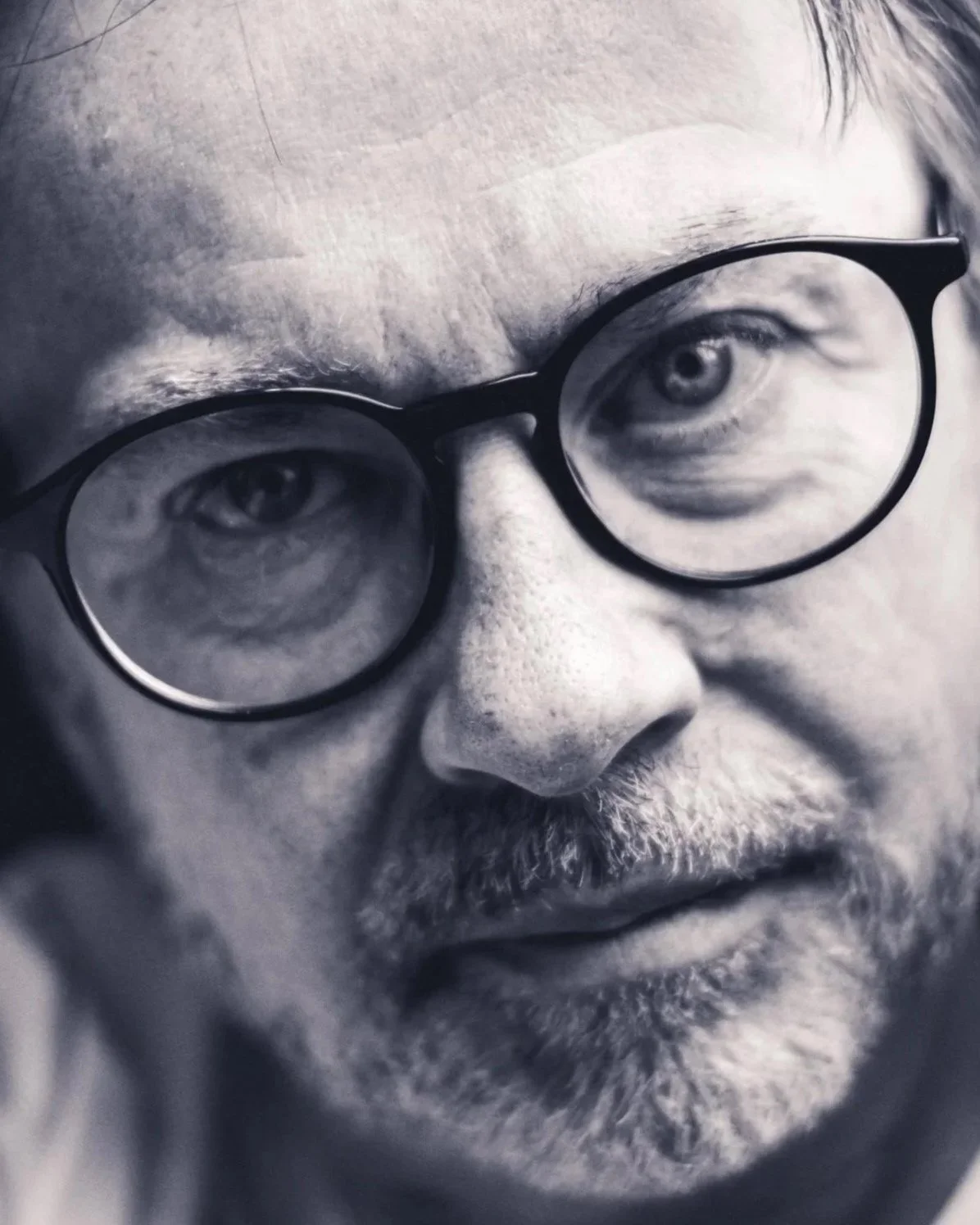 Monochrome close up photo of a James Warman with a beard and wearing glasses