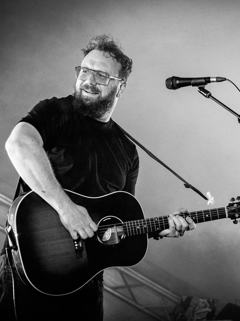 Black & white photo of a man playing an acoustic guitar on stage