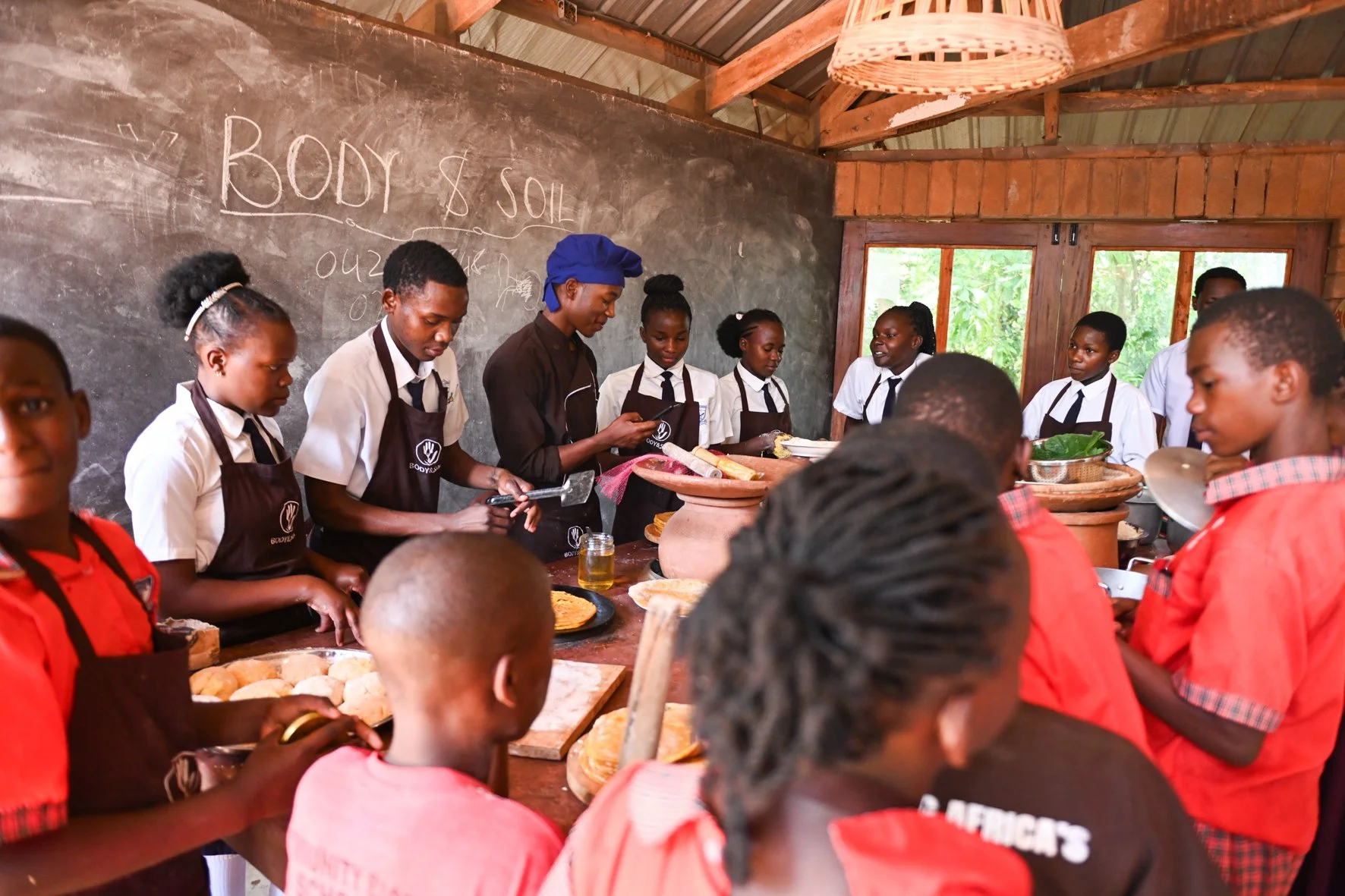 School children cooking in an energy saving kitchen with traditional clay pots in Ugnada.