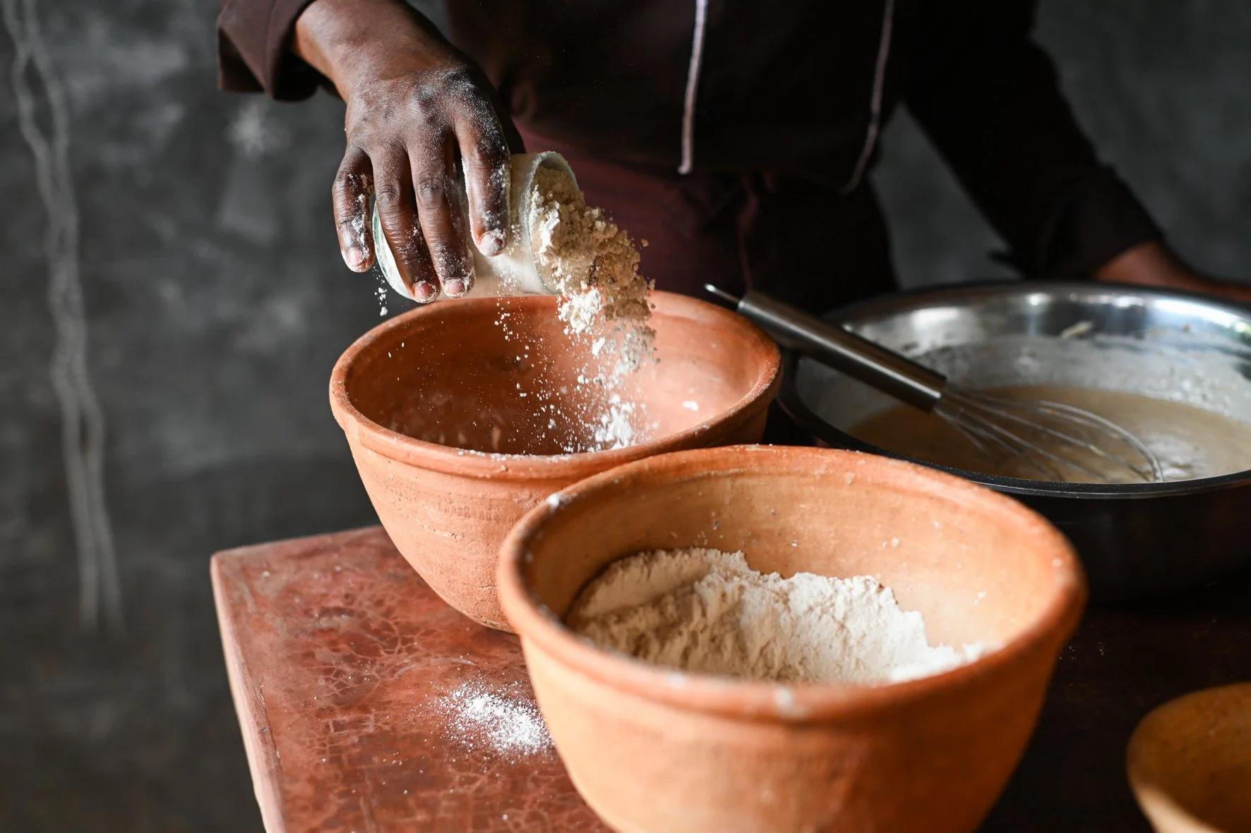 Bean flour being poured into a clay bowl.