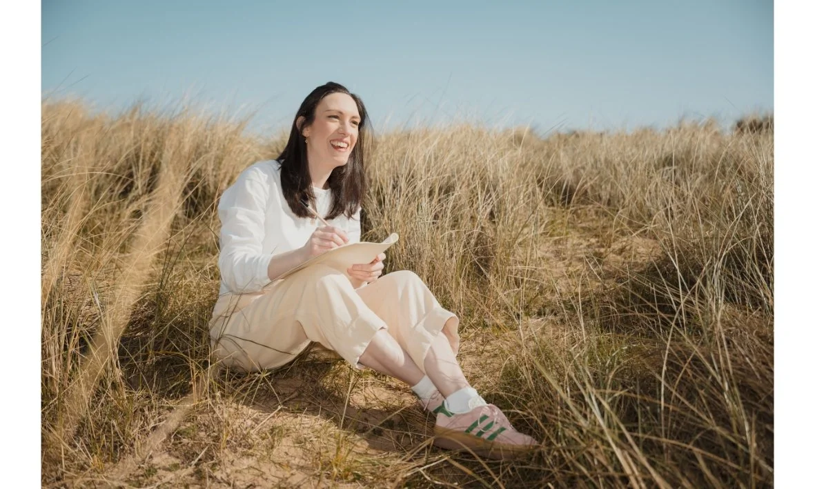 Woman sitting in sand dune and sketchingch