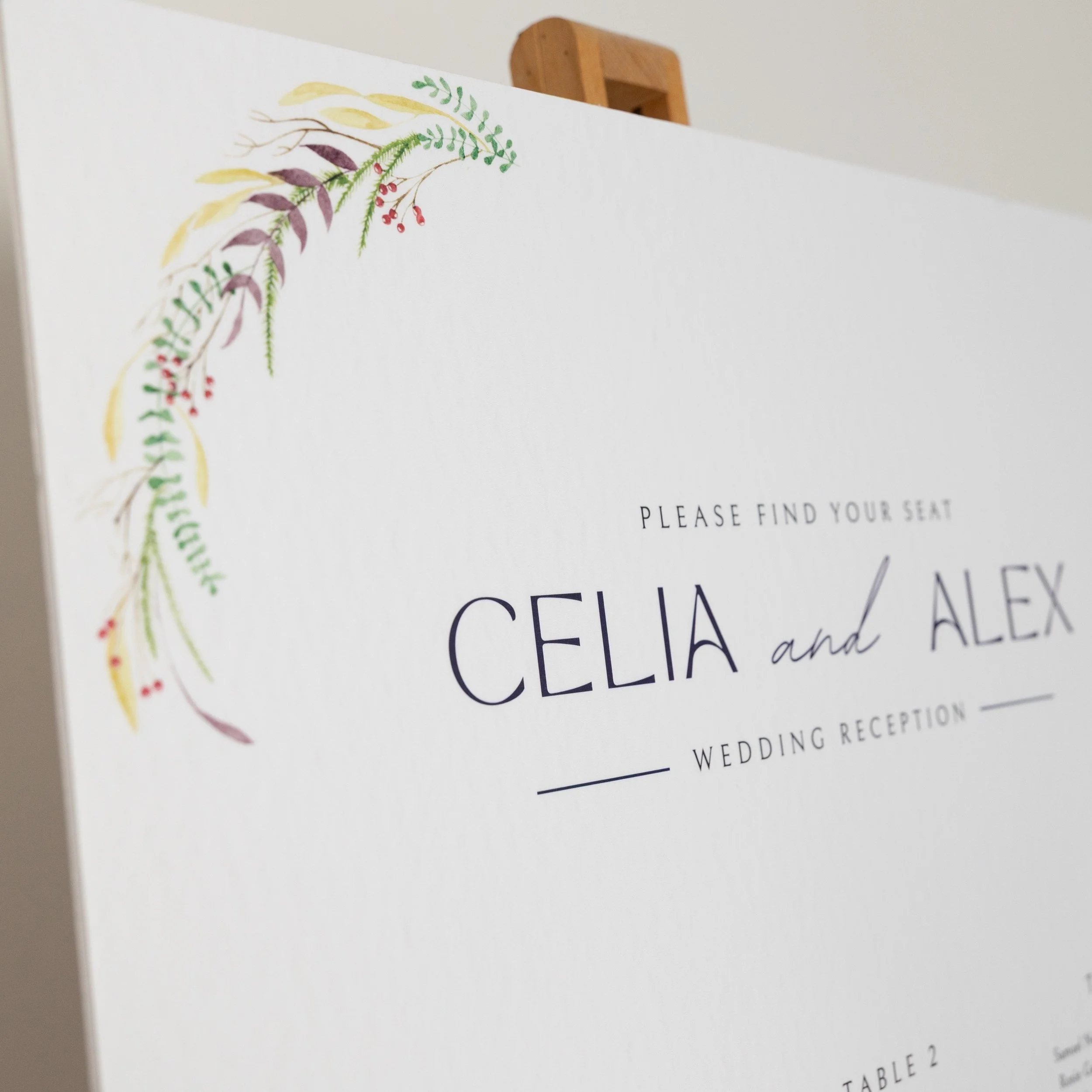 Close up of the corner of a wedding table plan with a handpainted winter motif featuring berries and foliage