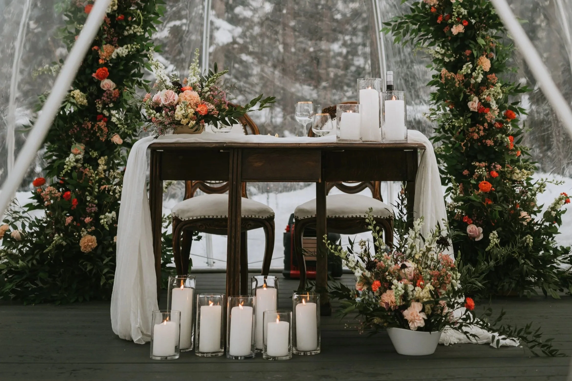 Outdoor ceremony arch for an Alaska elopement, decorated with florals and candles in a natural setting.