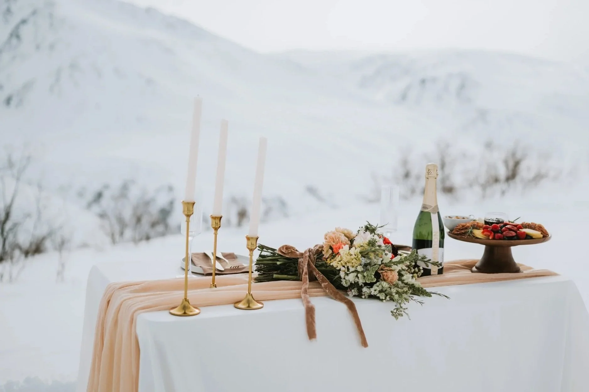 Minimalist table setting for a Denali elopement with mountain backdrop, styled with candles, florals, and natural textures.