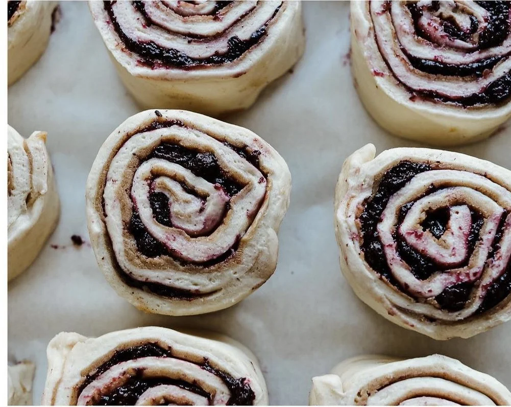 Unbaked cinnamon rolls swirled with a dark mixed berry filling