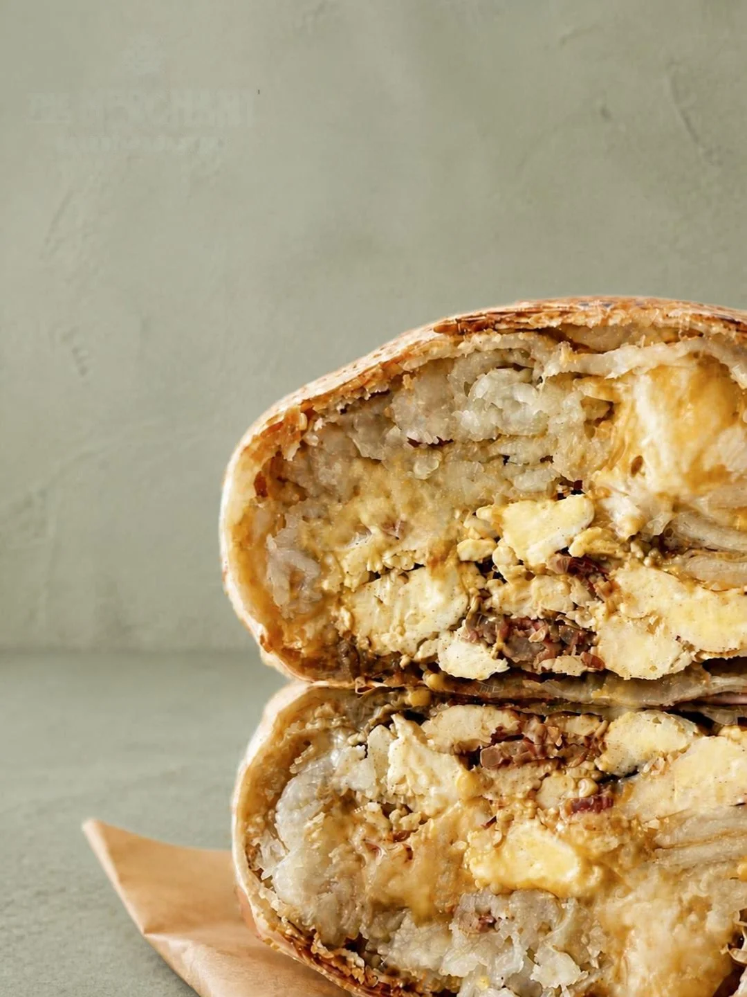 Two breakfast burrito halves stacked on paper wrap