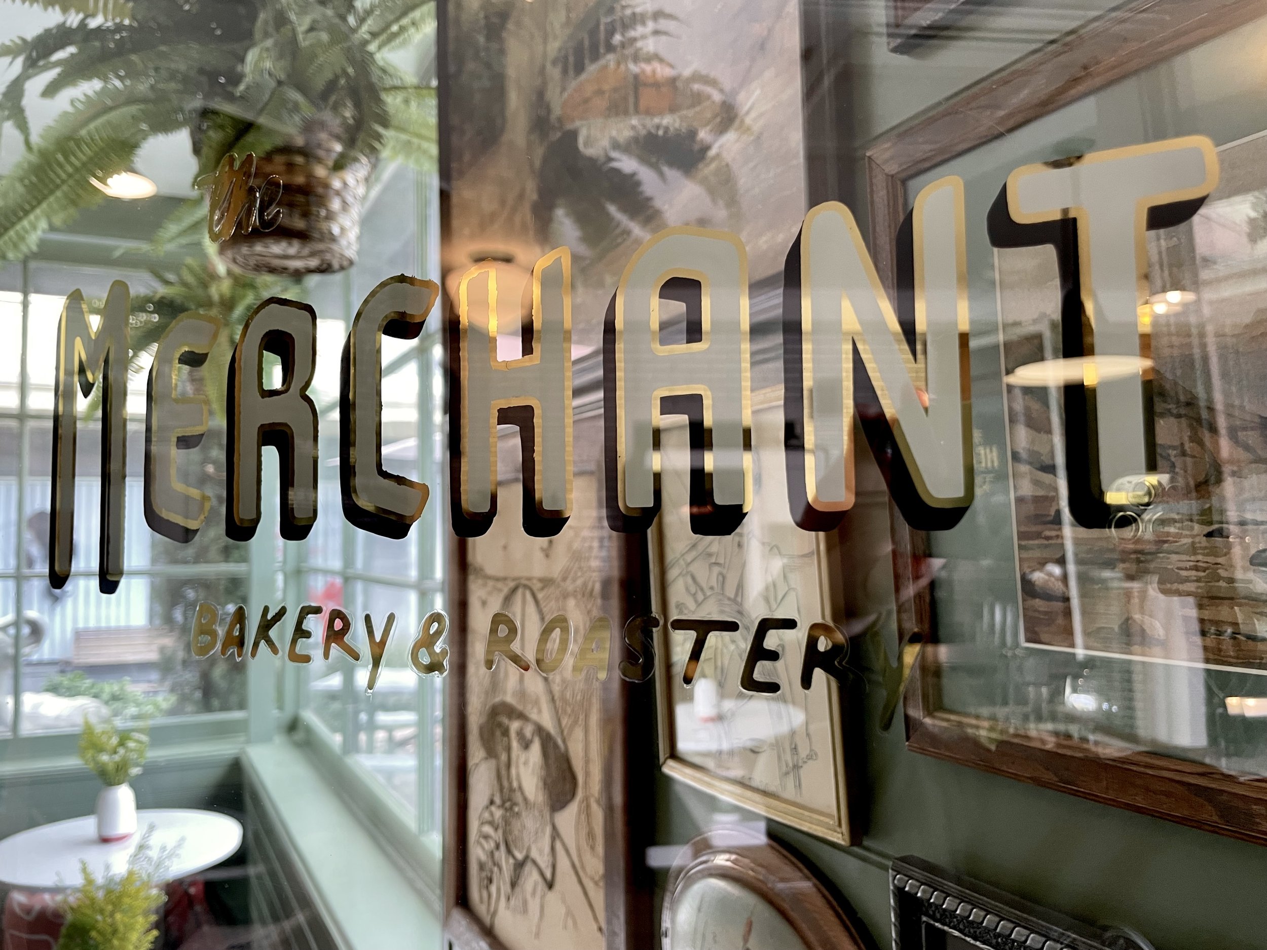 The Merchant Bakery & Roaster name painted in gold on the front window