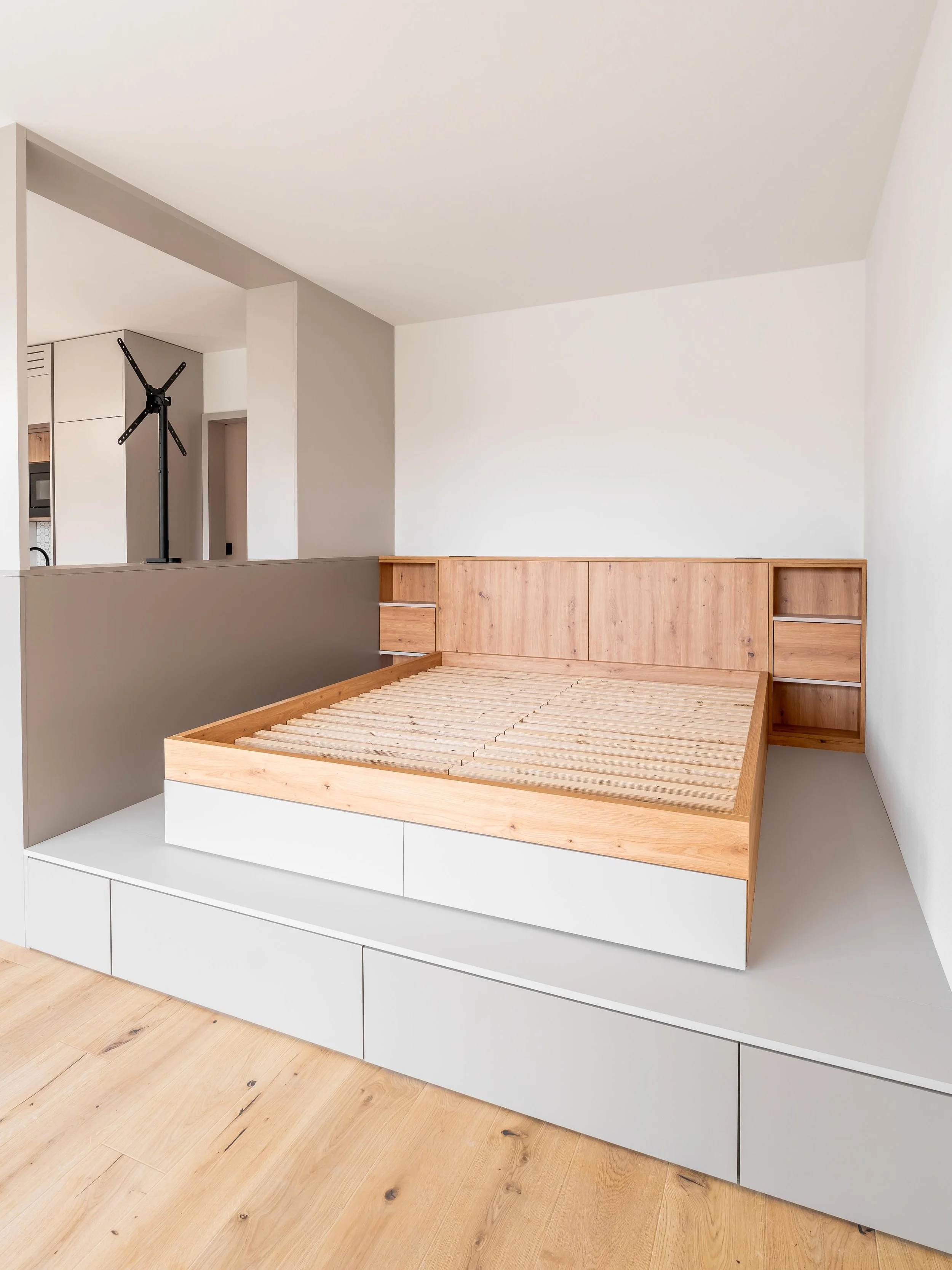 Spací část garsonky Šrámkovka s optickým oddělením a nábytkem v přírodních tónech