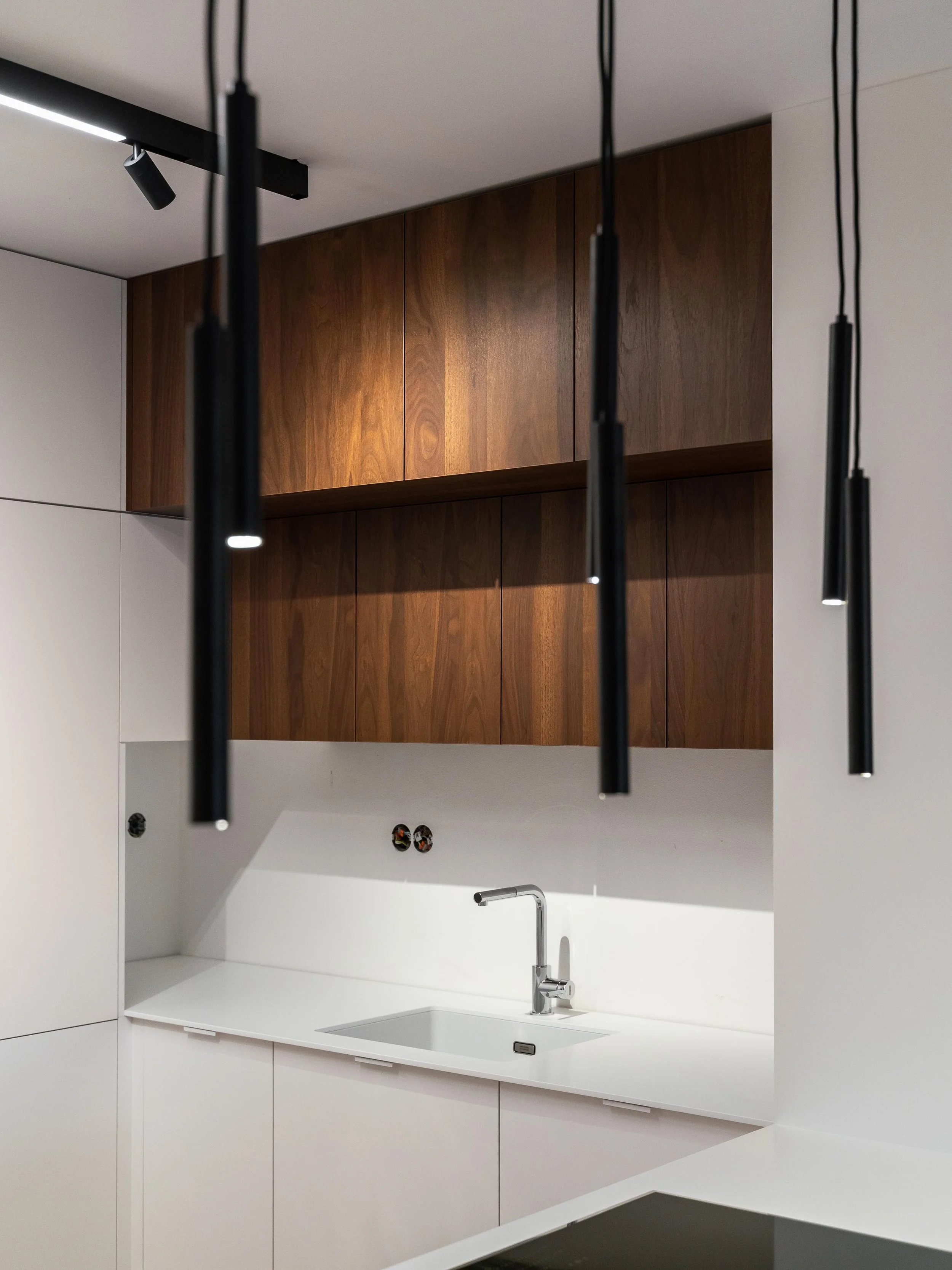 Elegantní kuchyňská linka na míru s bílými povrchy a dýhami Shinnoki v ořechovém dekoru