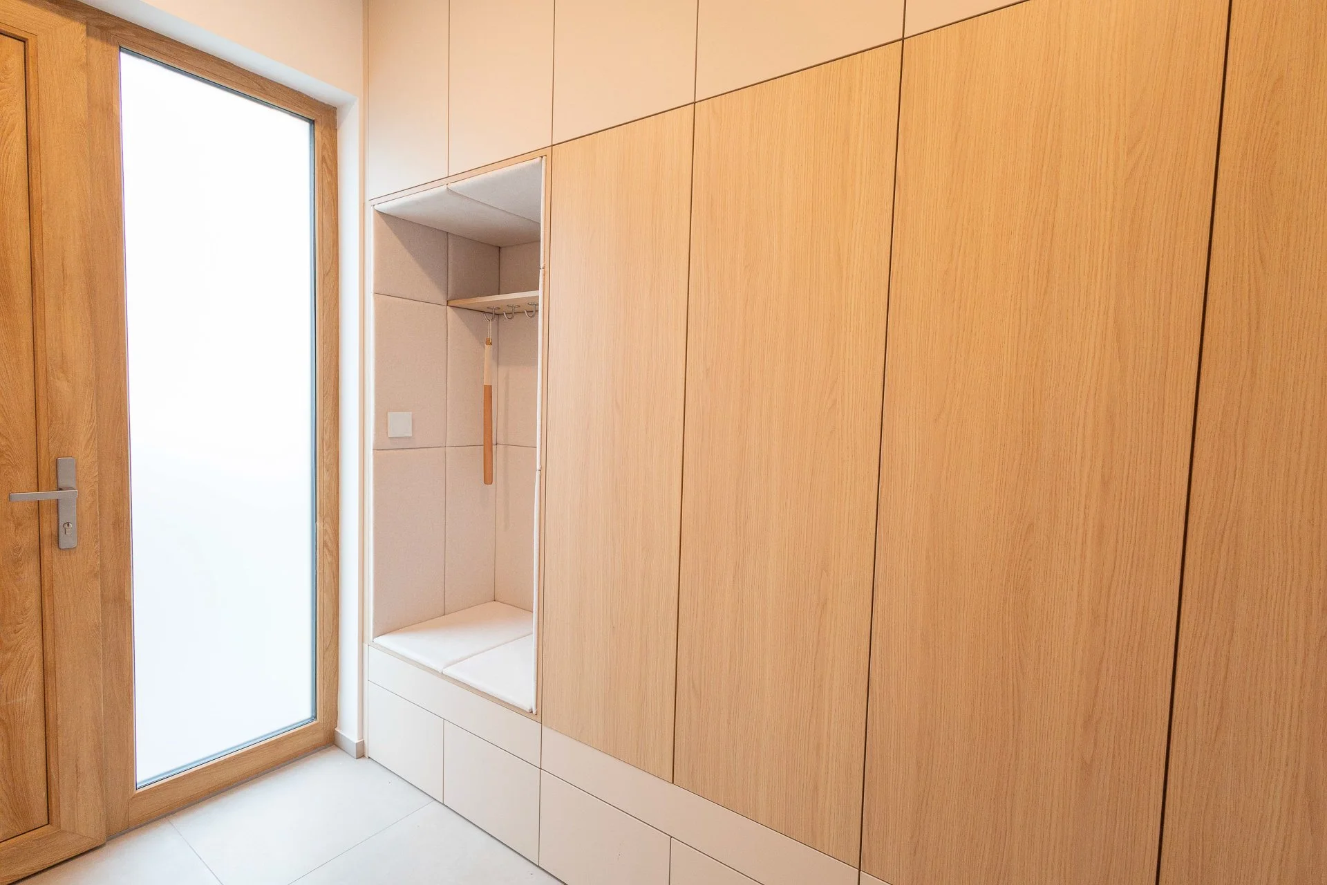 Celkový pohled na předsíň s lamelovým obkladem, závěsnou skříňkou a prosklenými posuvnými dveřmi - RD Hluboká nad Vltavou