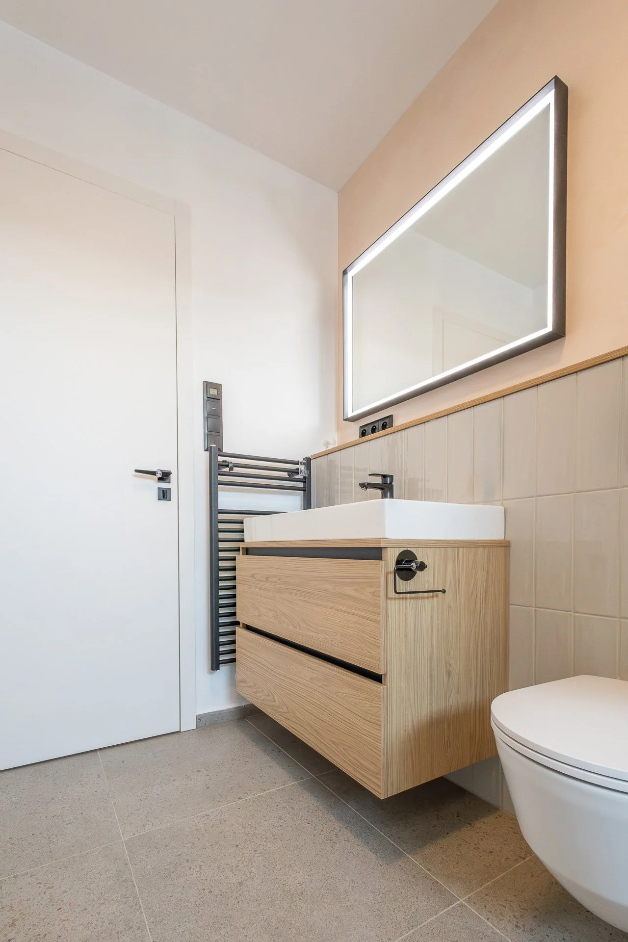 Dětská koupelna s dubovou skříňkou, zrcadlem s LED rámem a černou baterií (penthouse Šrámkovka, České Budějovice)